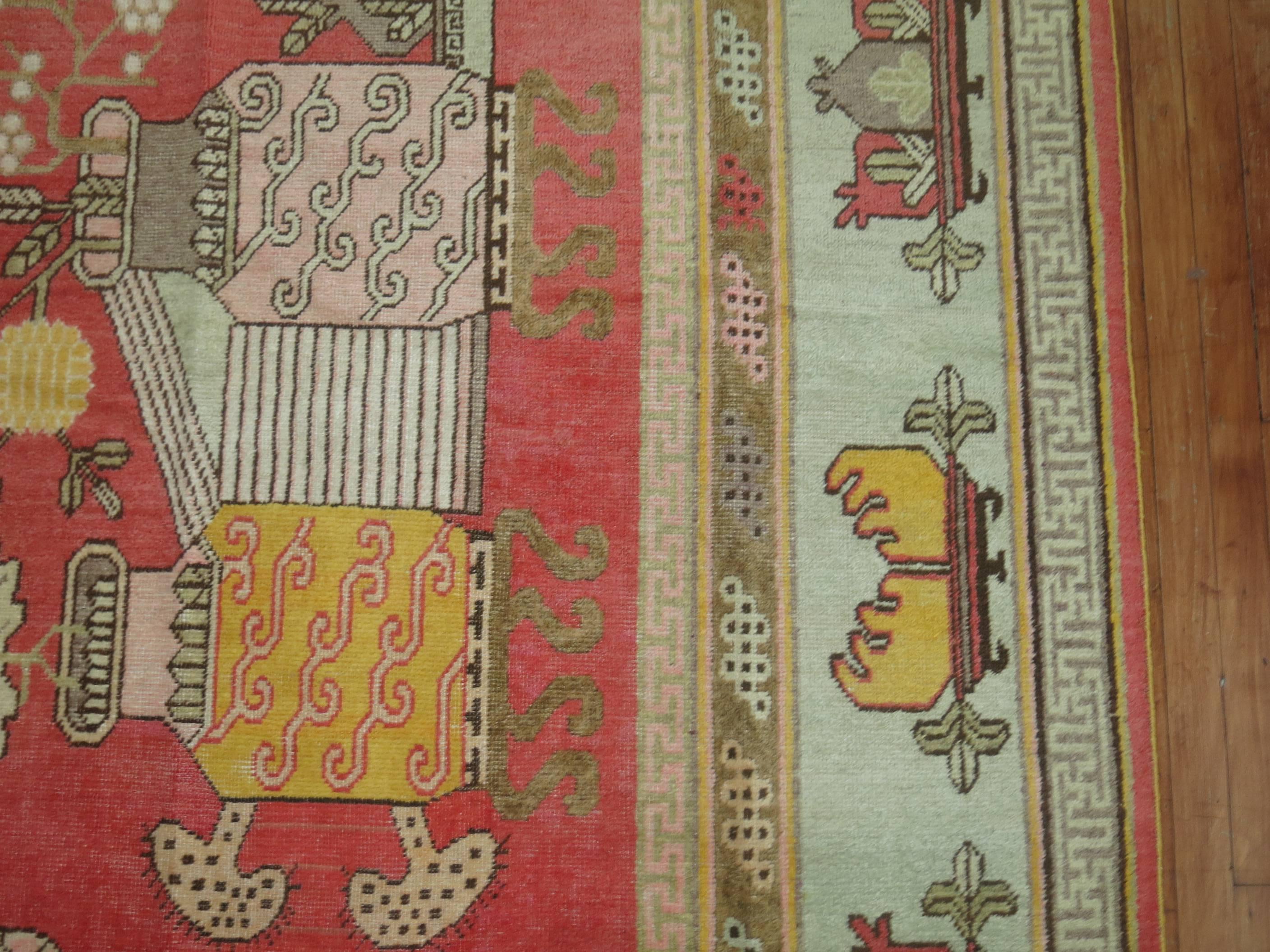 Grand tapis décoratif Khotan présentant un motif de vase de fleurs sur un fond rouge rosé doux. Produisant des tapis depuis le 17e siècle, avec un pic de production aux 18e et 19e siècles, les tapis de Khotan se caractérisent par des motifs