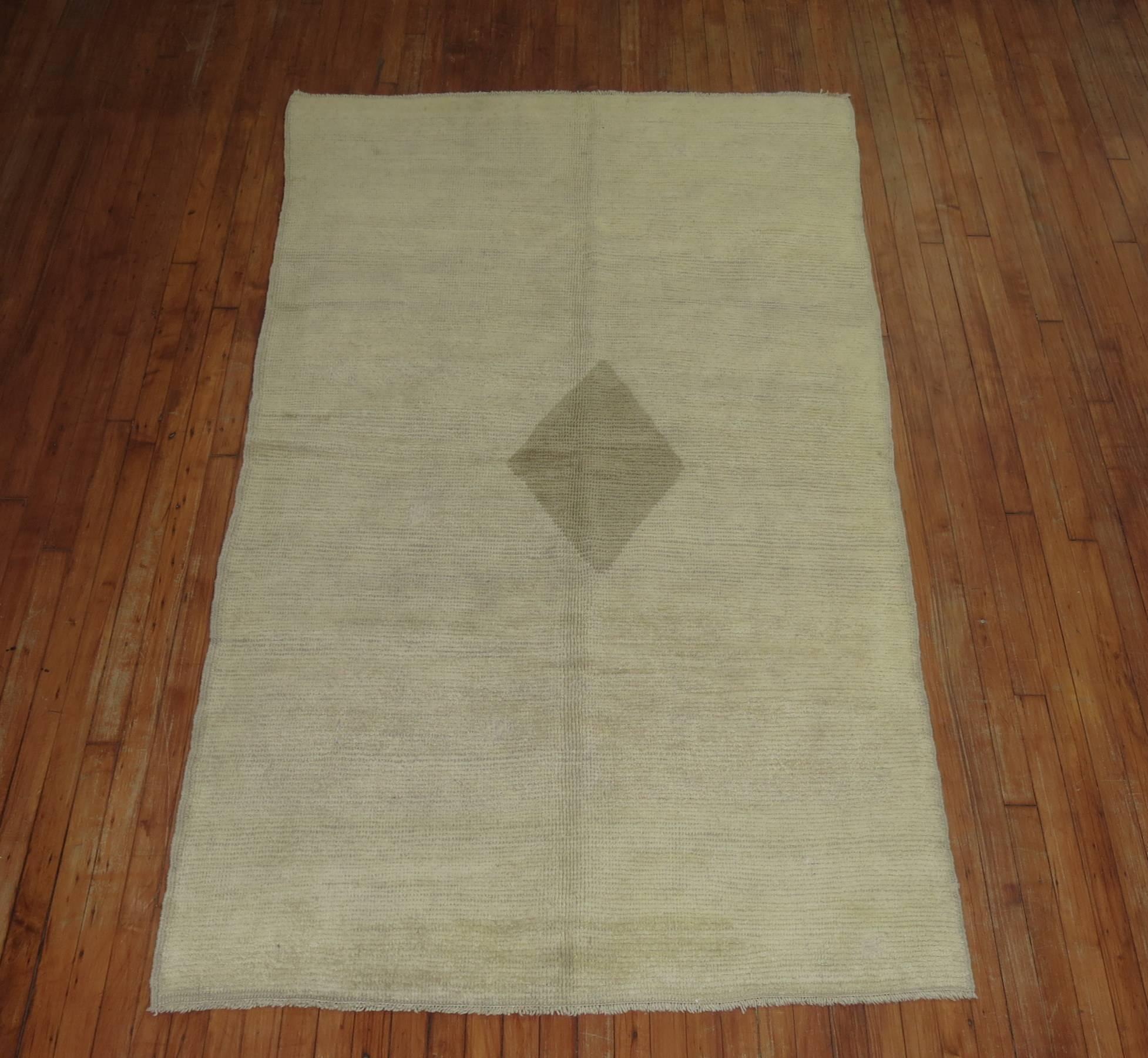 A contemporary styled vintage Turkish rug. Open cream ground with a soft brown off center diamond medallion on a khaki ground, mid-20th century.


Measures: 4'5'' x 7'11''.