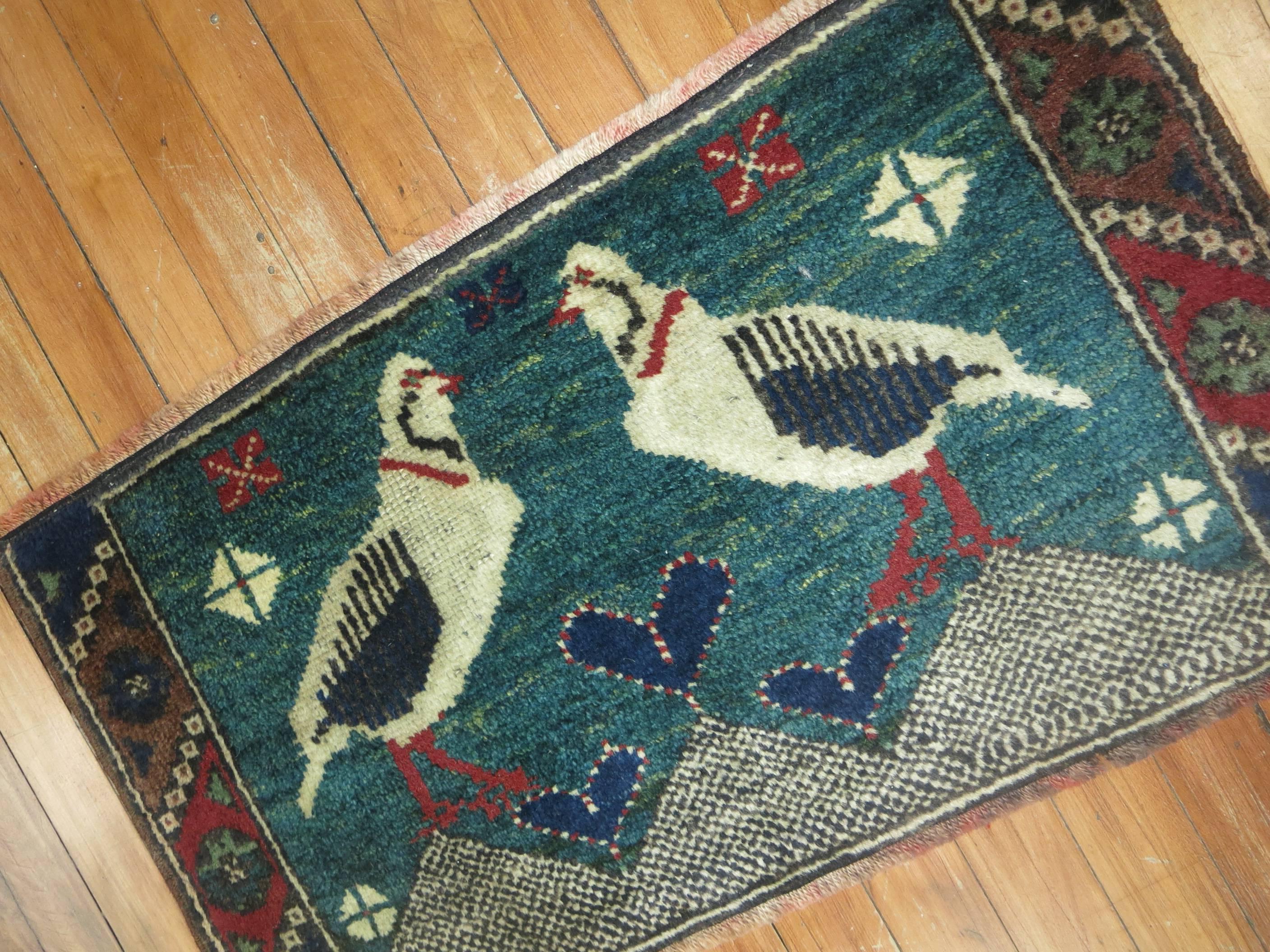 Vintage Persian pictorial throw rug with two pigeons standing and staring at each other.