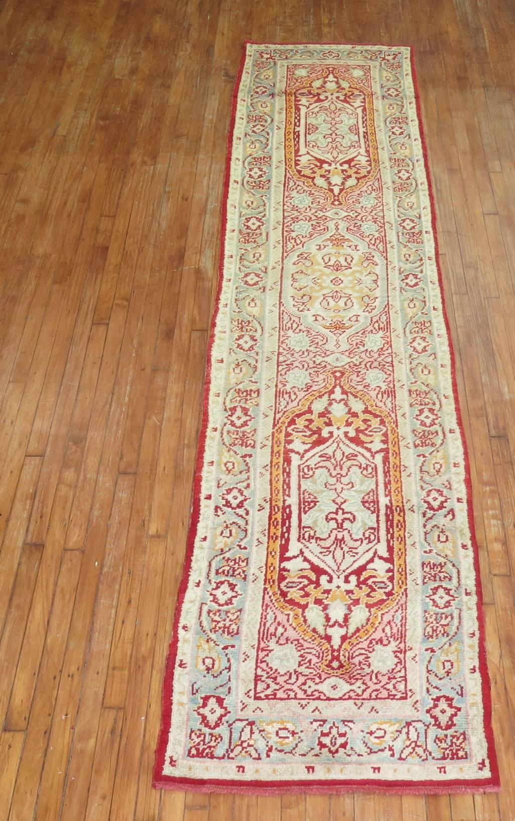 An early 20th century elegant handmade antique Turkish Oushak runner featuring three medallions on a pinkish red field surrounded by a mint green border.

Measures: 2'9