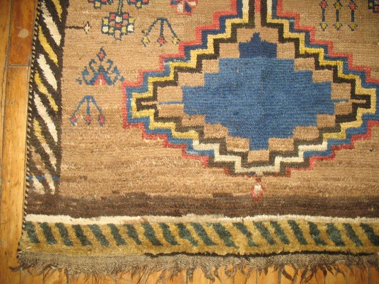 A tribal antique Persian Gabbeh in camel, creams, yellow, browns and rusts.

Antique Gabbehs rugs are tribal Persian rugs made with extra high pile and very simple, graphic designs focused on the use of color, which can be vibrant or soft and
