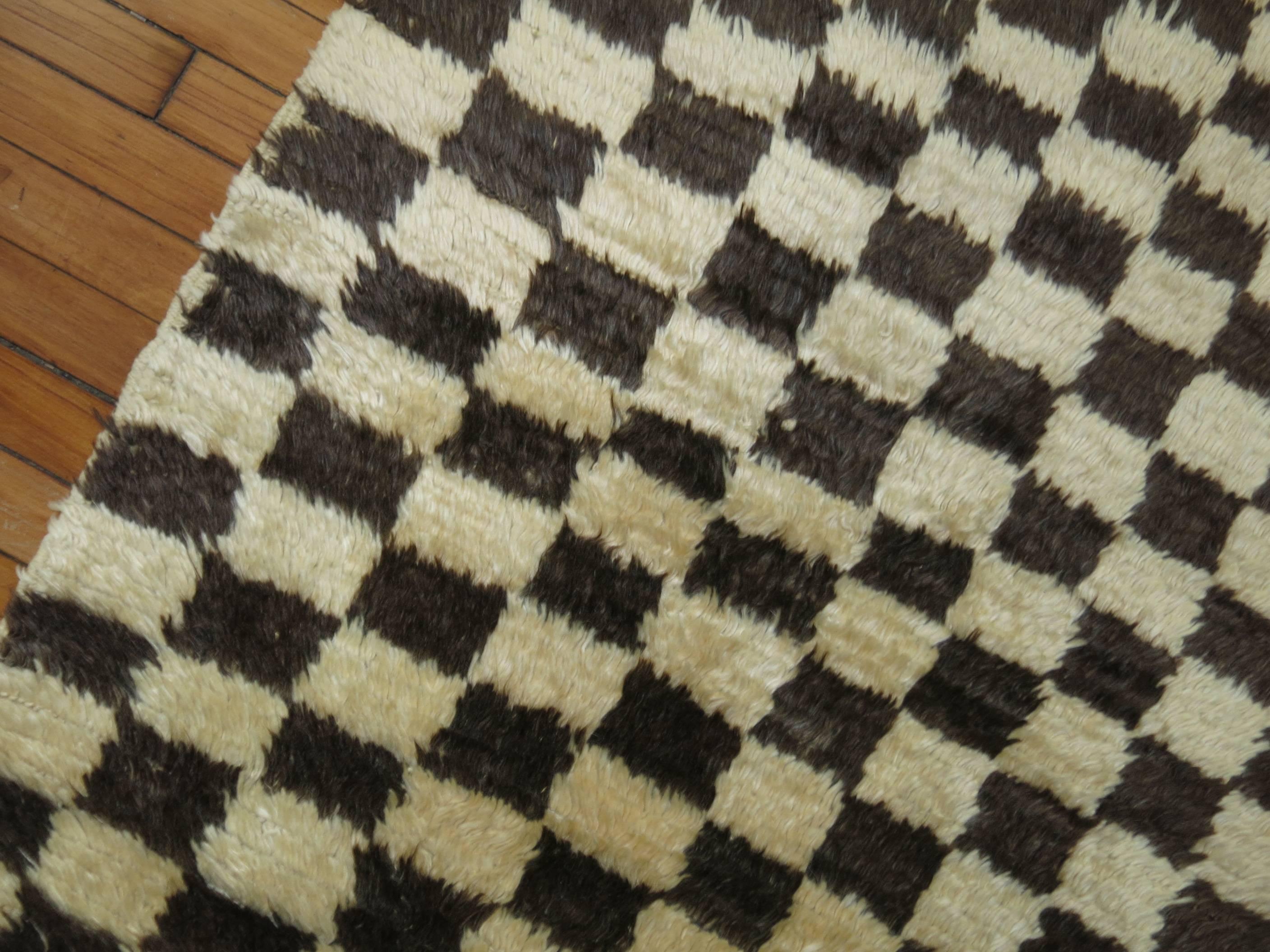 A mid-20th century turkish rug featuring a checkerboard design in brown and beige.