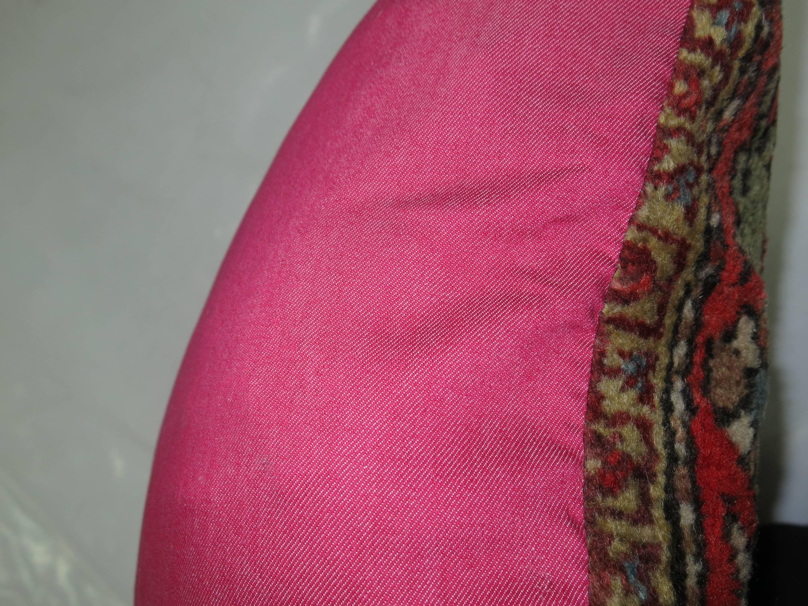Pillow made from an early 20th century Persian rug backed in bright pink.