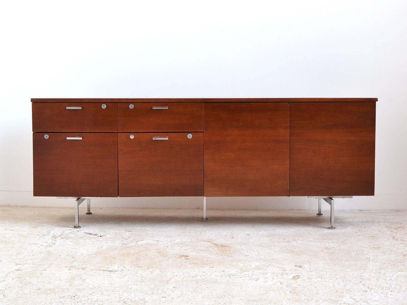 This handsome credenza by Robert John features a walnut case supported by chromed steel legs that remind us of designs by Hans Wegner. It has two shallow drawers above two deep drawers and two open cabinets, one with an adjustable shelf, the other