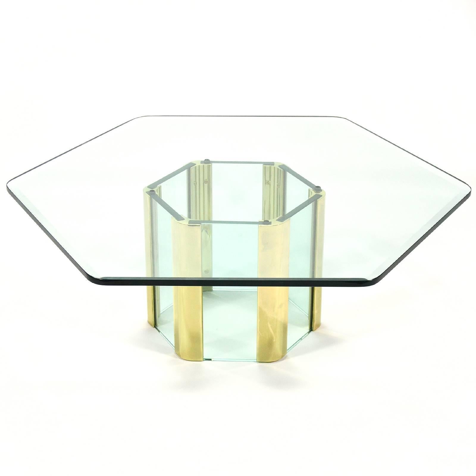 A beautiful design which is both substantial and visually light with its generous use of glass. This hexagonal cocktail table has a base of thick glass connected with the distinctive brass connecting elements. It supports a nicely detailed top with
