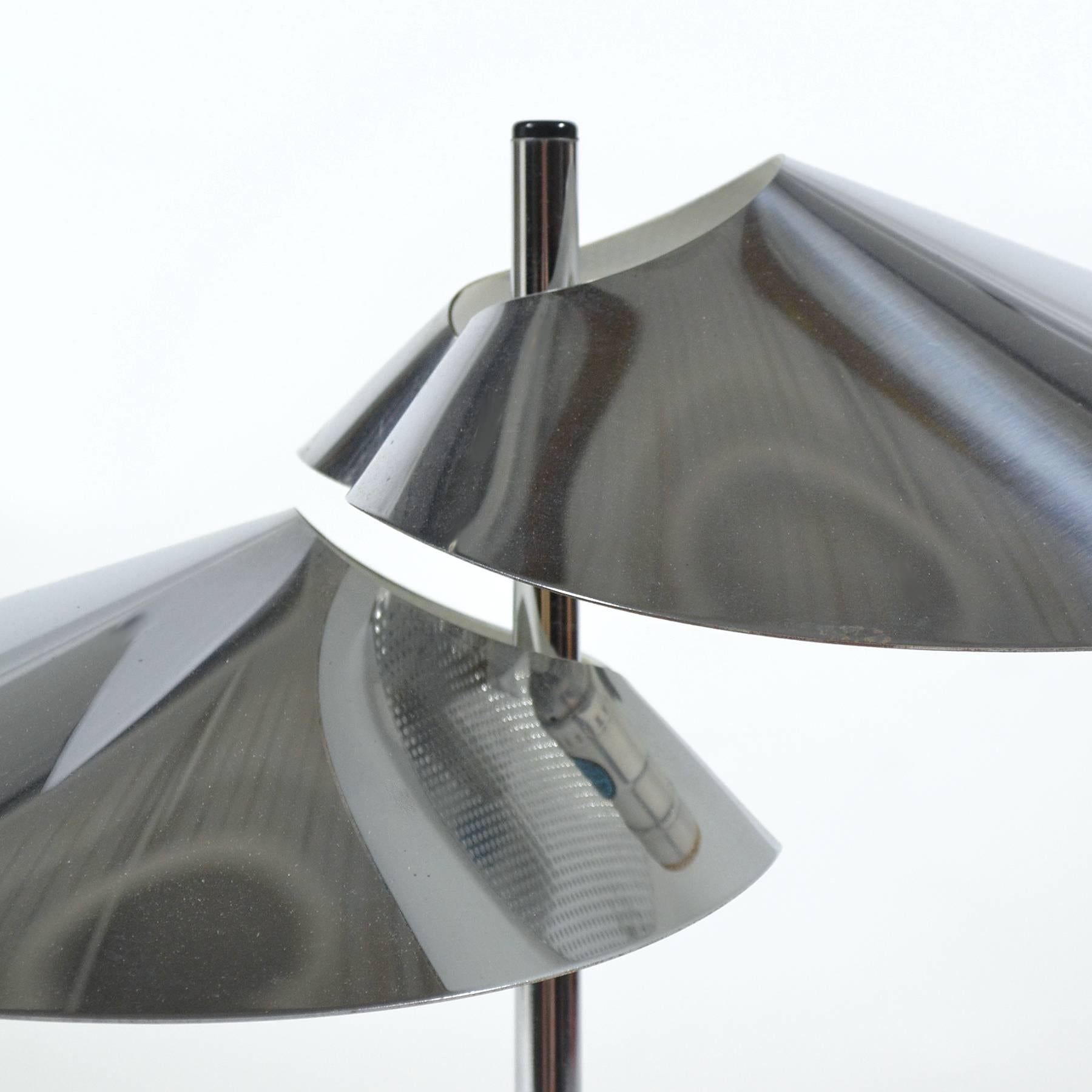 A subtle, elegant design by Jere, this table lamp has two heads of chromed steel which have been bent and folded into beautiful visor shapes. A perforated diffuser at the top of each allows heat to escape and prevents glare.