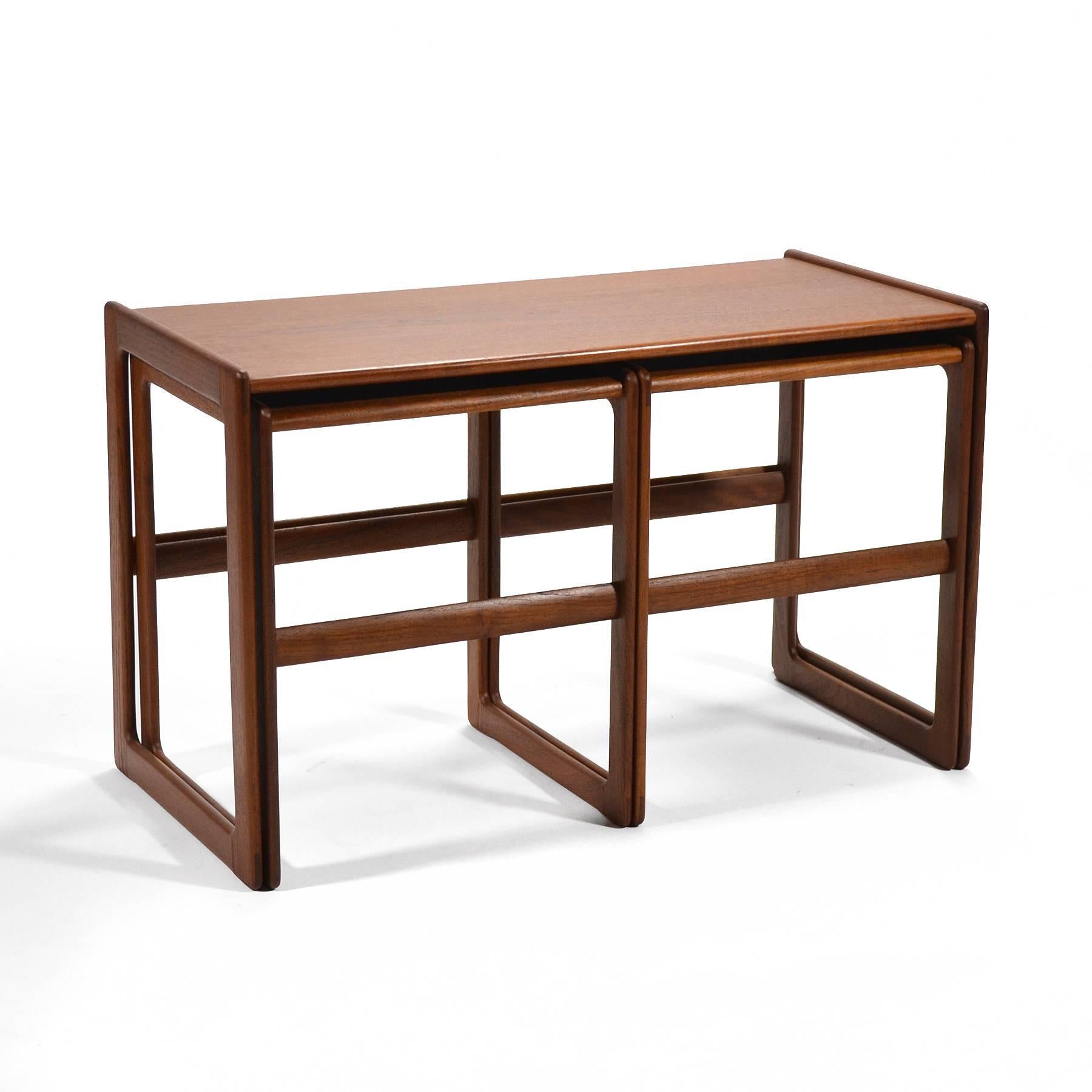 This lovely set of teak nesting tables in teak are not only handsome, they are incredibly versatile. The two smaller tables nest side-by-side under the larger table. With curved corners, raised edges, and exquisite joinery, they offer several