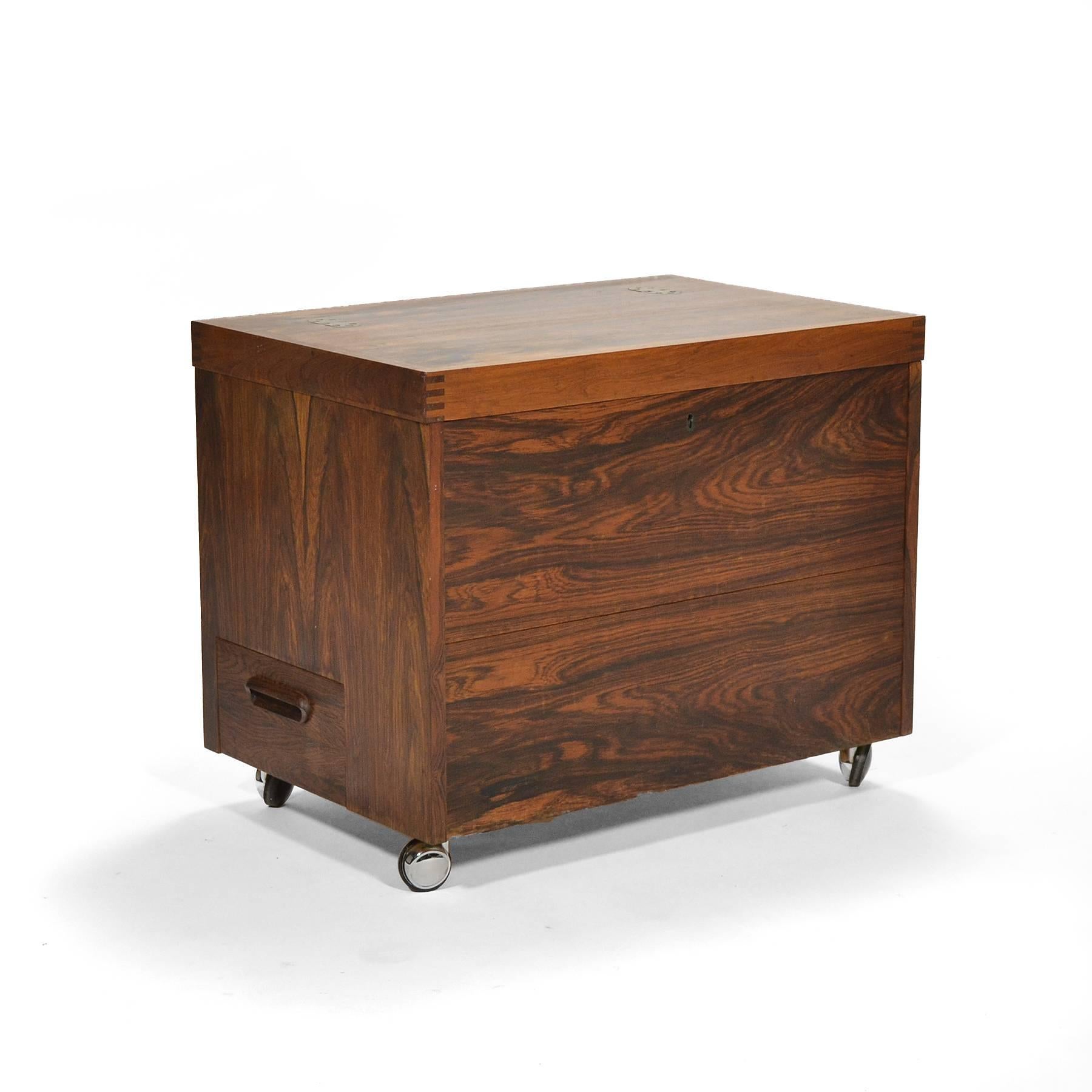 This delightful piece designed by Rolf Hesland and crafted by Haug Snekkeri for Bruksbo serves double duty as both a side table and a small portable bar. It has great presence with beautifully figured rosewood, nice brass hinges and exposed joinery.