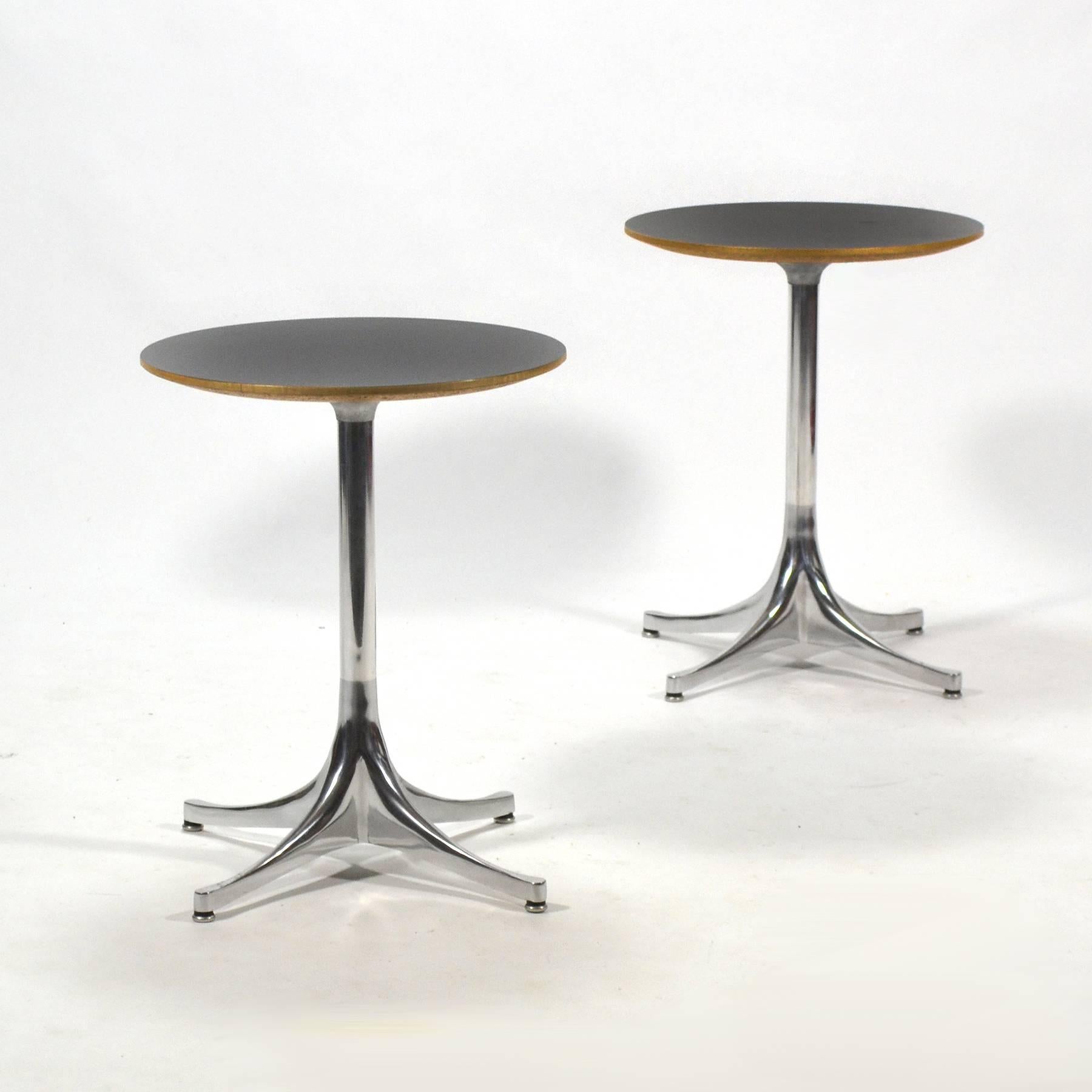 This nice pair of side or end tables are a Classic Nelson design. We love the proportions of this version with the small tops. The cast aluminium bases are unpainted they have a lovely patina and support tops of black mica with a birch edge band.
