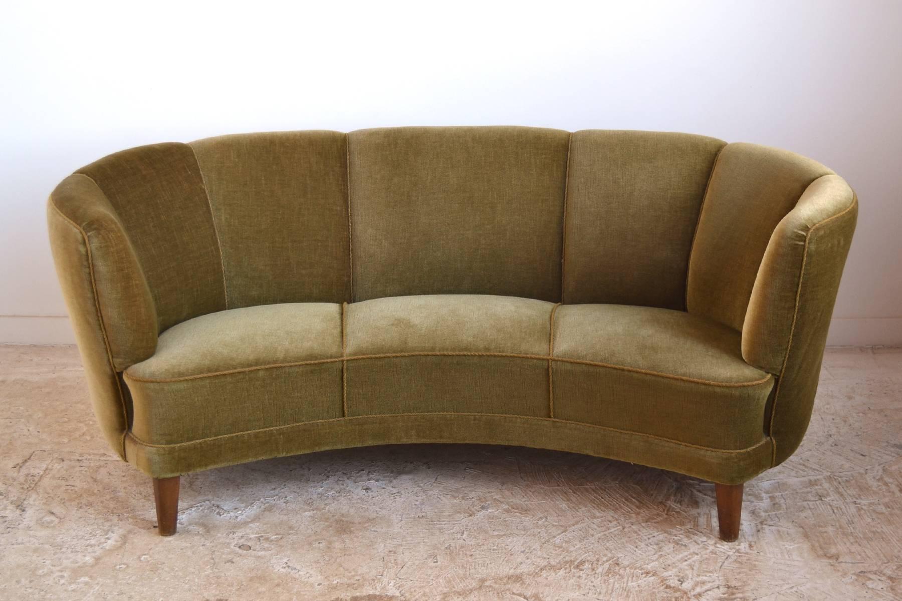 This Swedish sofa represents a transition from the Deco/ Moderne to Mid-Century Modern aesthetic. The elegantly curved form has less adornment, but still retains some very lovely details. It is supported by conical legs in the front, while the back