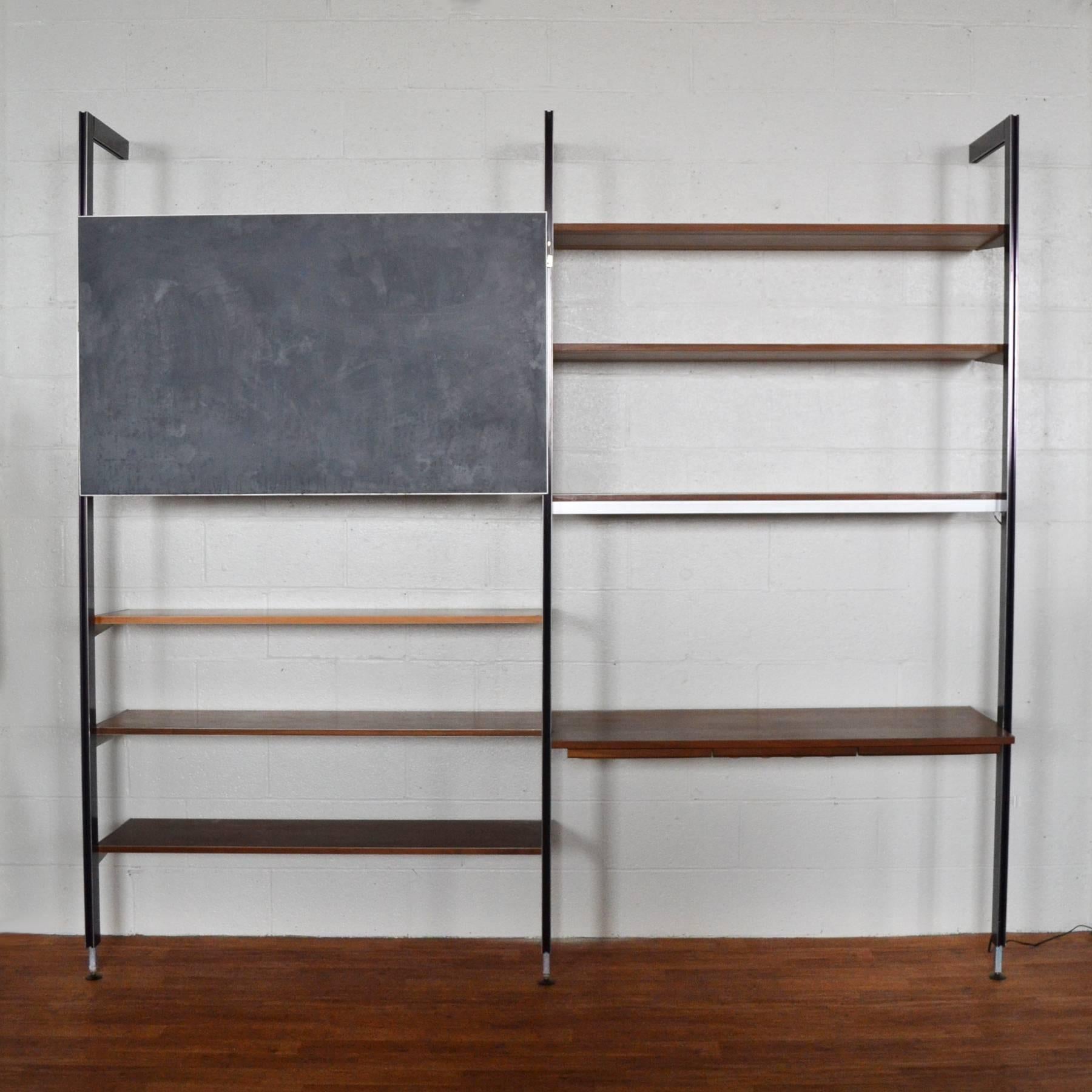 This CSS shelving unit is a very uncommon example. The beautiful Minimalist design is comprised of three tension-mounted uprights supporting six shelves, a desk with three drawers, and a rare chalkboard. One shelf has a lamp mounted to the underside