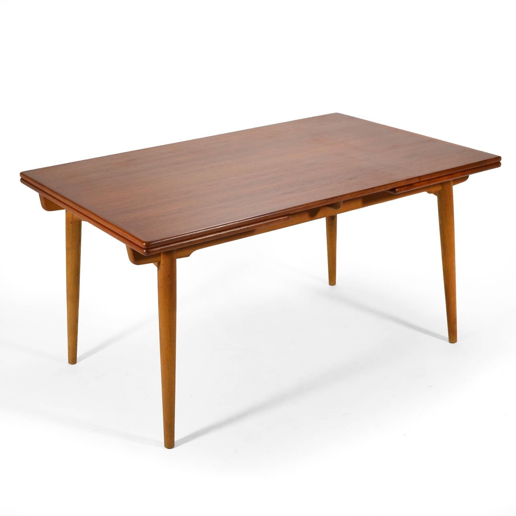 A masterwork by Hans Wegner, the AT312 dining table has a top of teak supported by an oak base. It features two 19.5