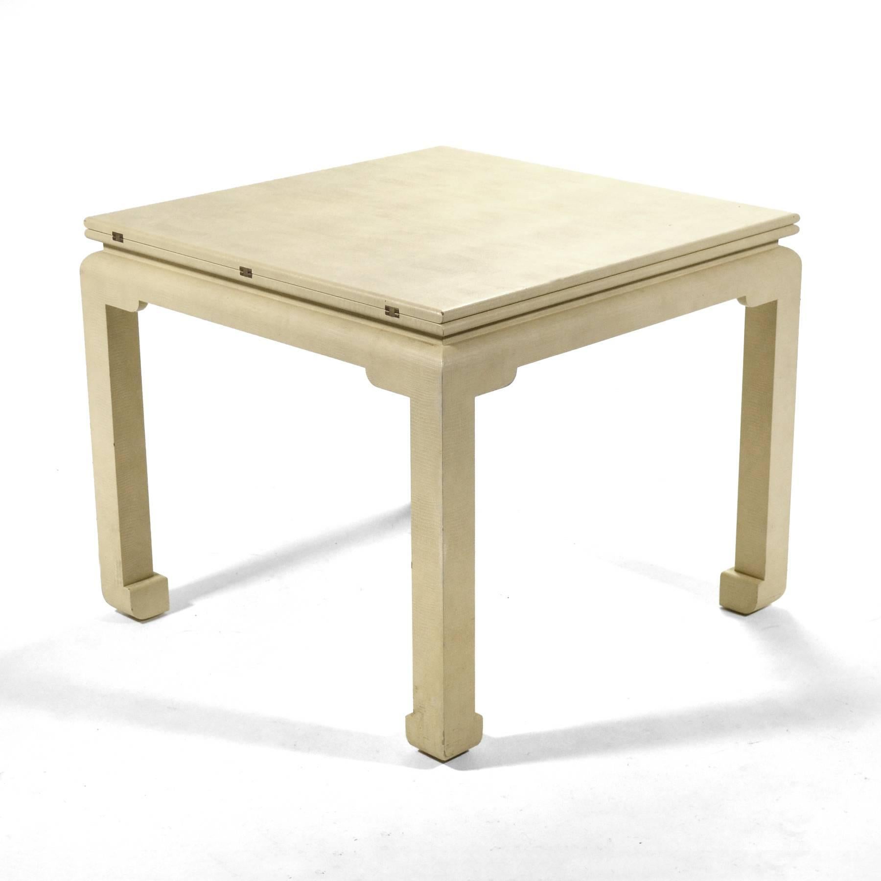 This striking game table by Karl Springer is clad in ivory snake-embossed leather and has a top that flips open to double in size allowing it to serve as a dining table.