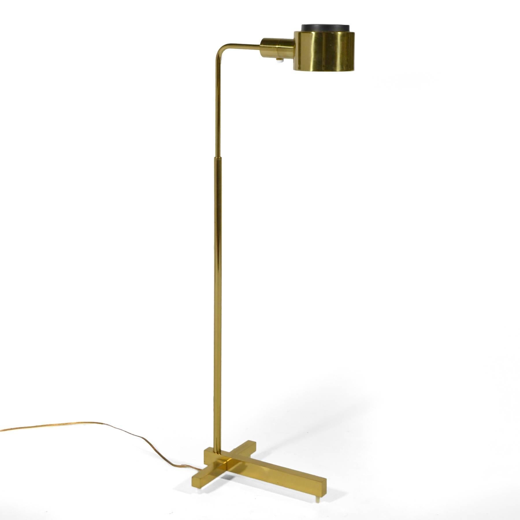 This wonderful pharmacy floor lamp designed by Jon Norman for Casella is impeccably constructed of solid brass. The heavy cruciform-shaped base is raised on slender feet and supports and adjustable neck that’s topped with a cylindrical shade that