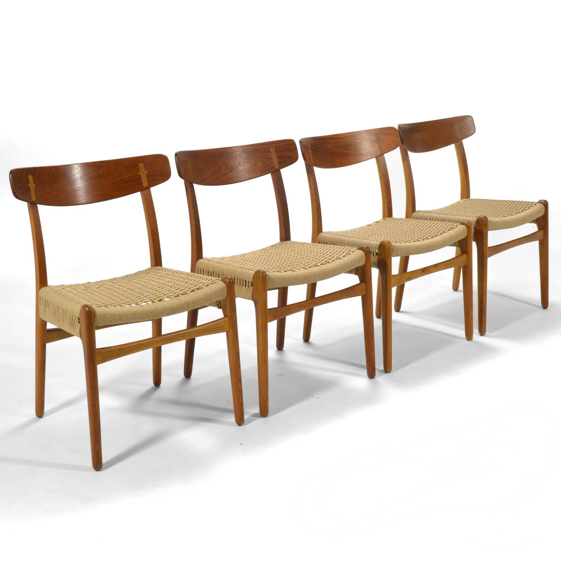 This handsome set of four Hans Wegner CH23 chairs were expertly crafted by Carl Hansen & Søn. The feature oak frames with teak backrests and papercord seats. They are in excellent condition, the frames have been cleaned retaining their original