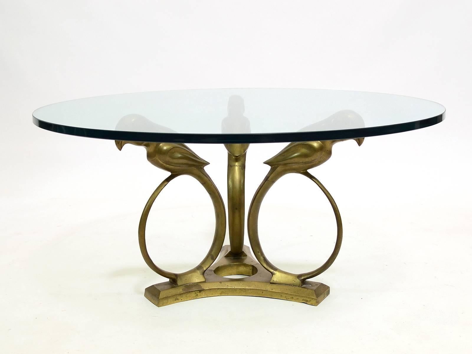 This lovely table in the manner of Alain Chervet has a solid brass base in the form of three streamlined parrots on a reverse trefoil base which supports a thick glass top.