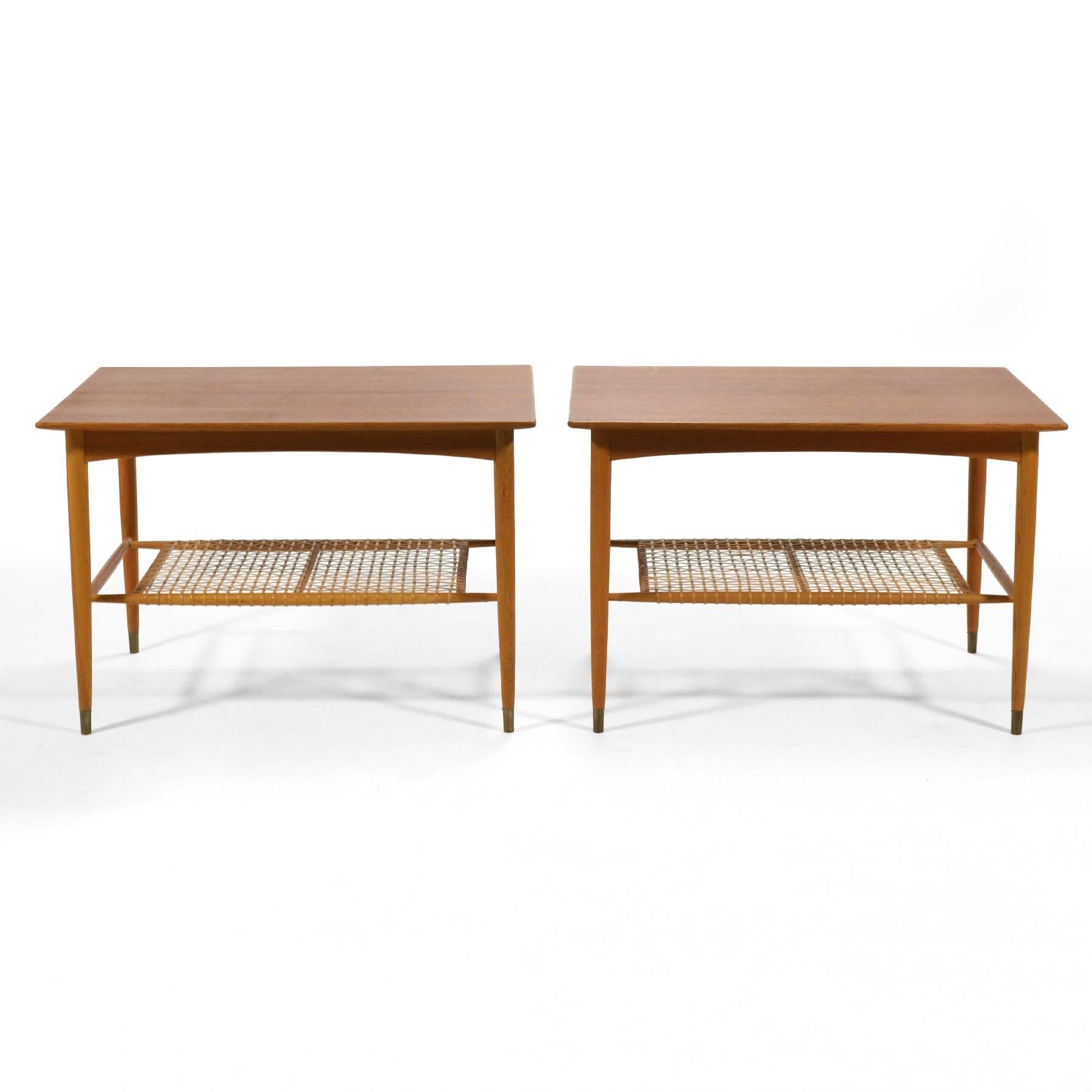 These Folke Ohlsson side tables have beautiful lines and wonderful proportions. They are expertly crafted of teak and oak and feature a woven cane shelf and brass capped feet.