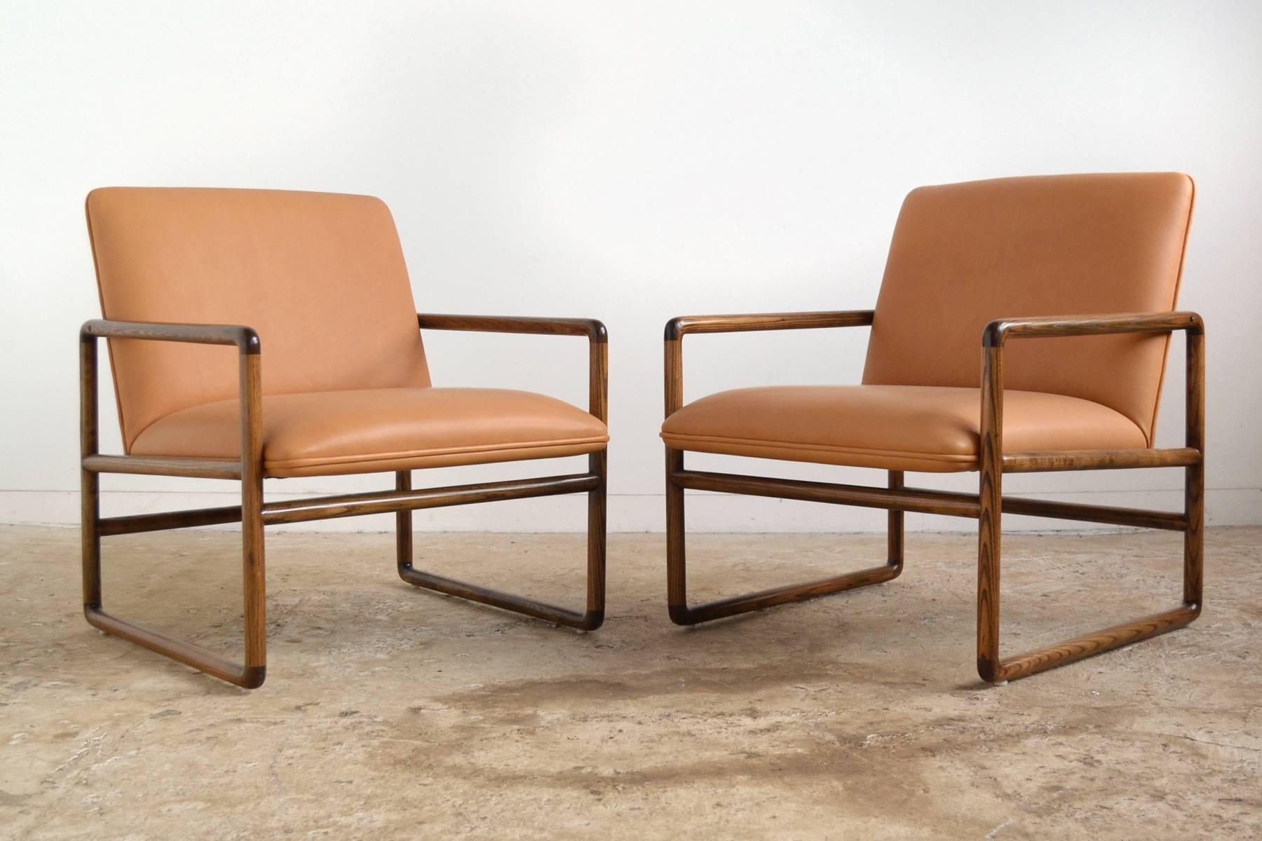 This pair of elegant, understated lounge chairs by Ward Bennet epitomize his design aesthetic: combining a refined sensibility with top quality materials and construction. These lounge chairs have exterior frames of ash which support seats and backs