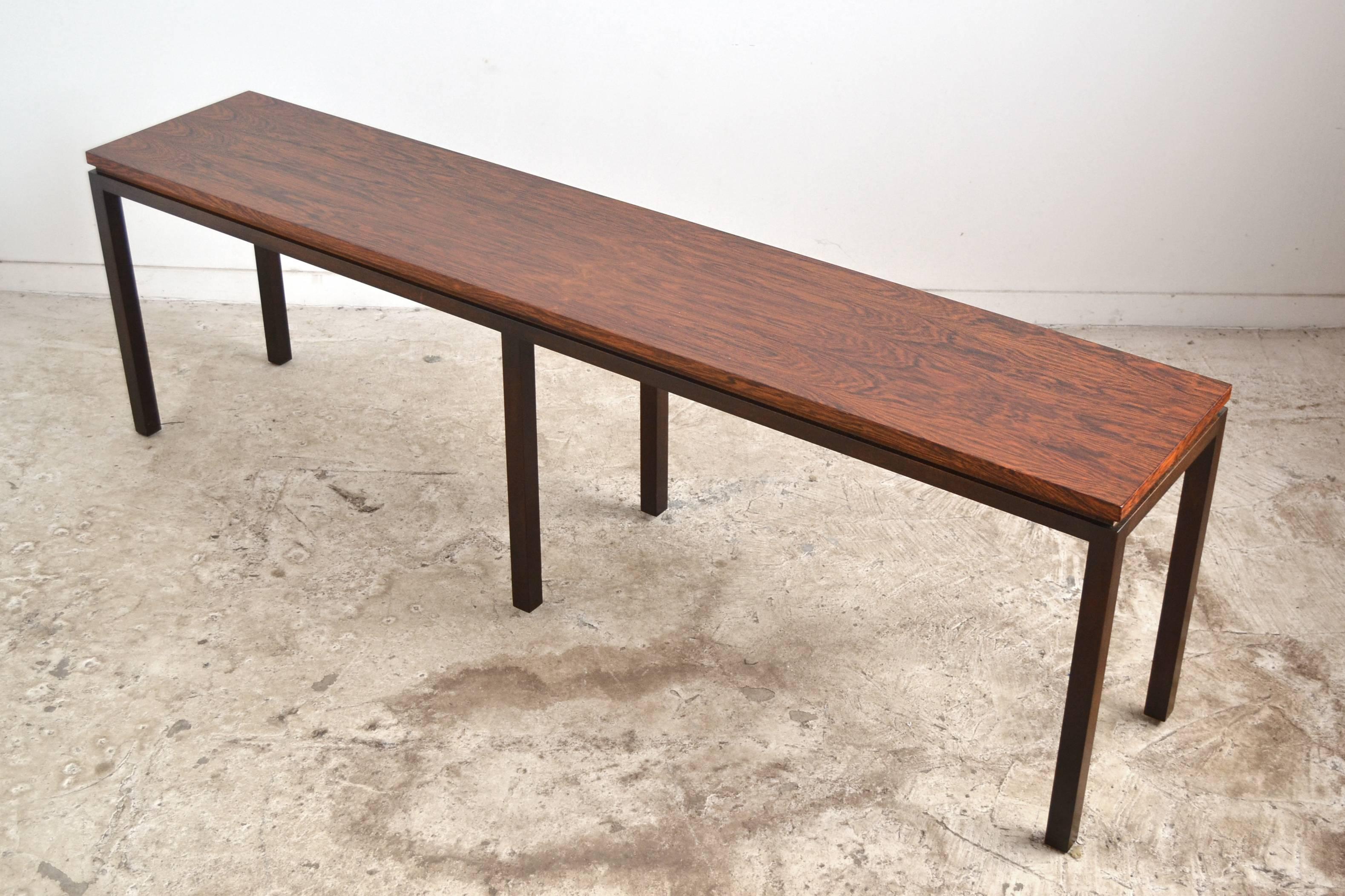A long, lovely sofa or console table by Harvey Probber with a top of rich rosewood supported by a dark mahogany base.