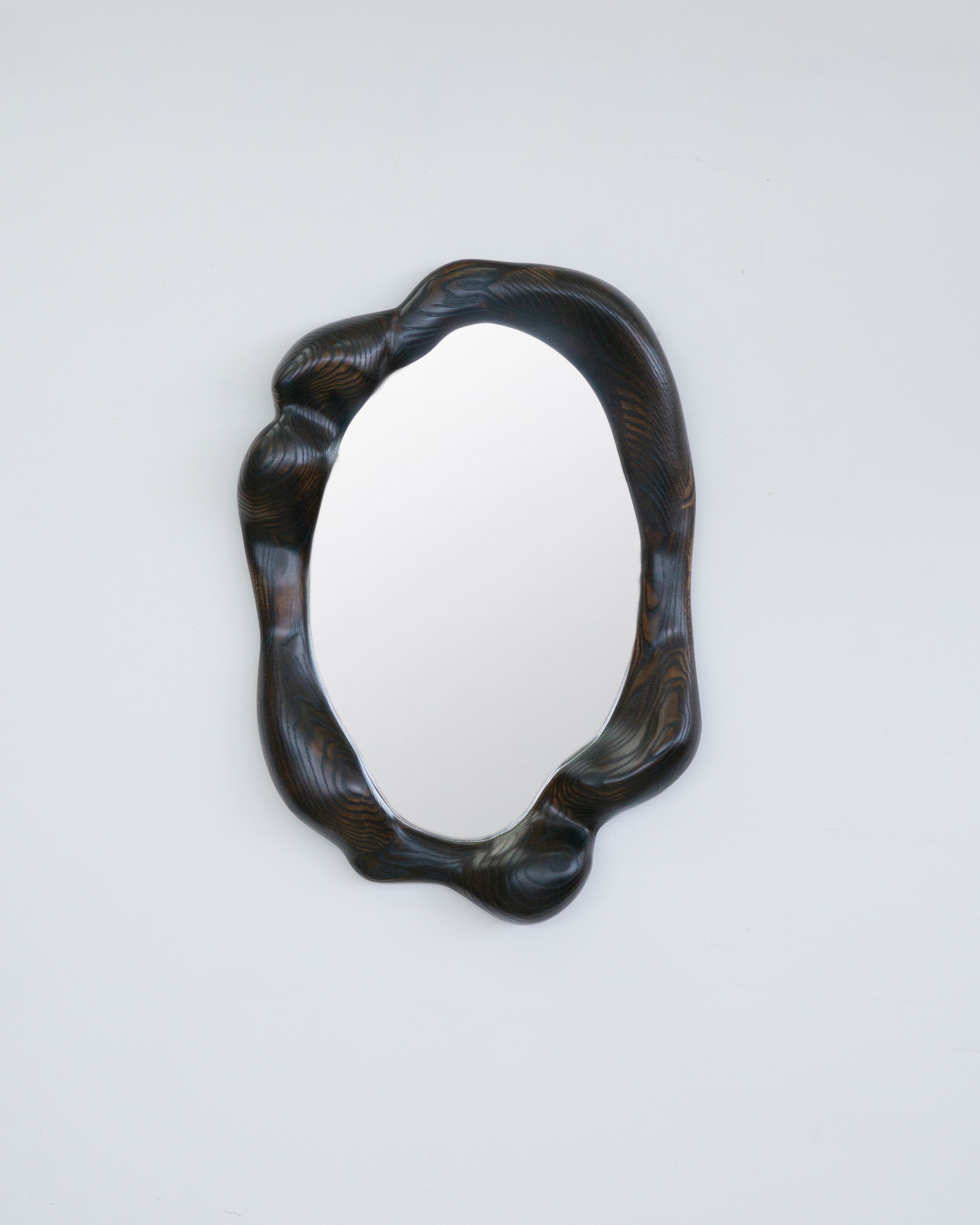 La cornice dello specchio viene modellata con vari strumenti manuali, rendendo ogni pezzo unico con le sue caratteristiche venature del legno. Lo specchio è realizzato in quercia rossa di alta qualità, leggermente bruciata e rifinita con olio di