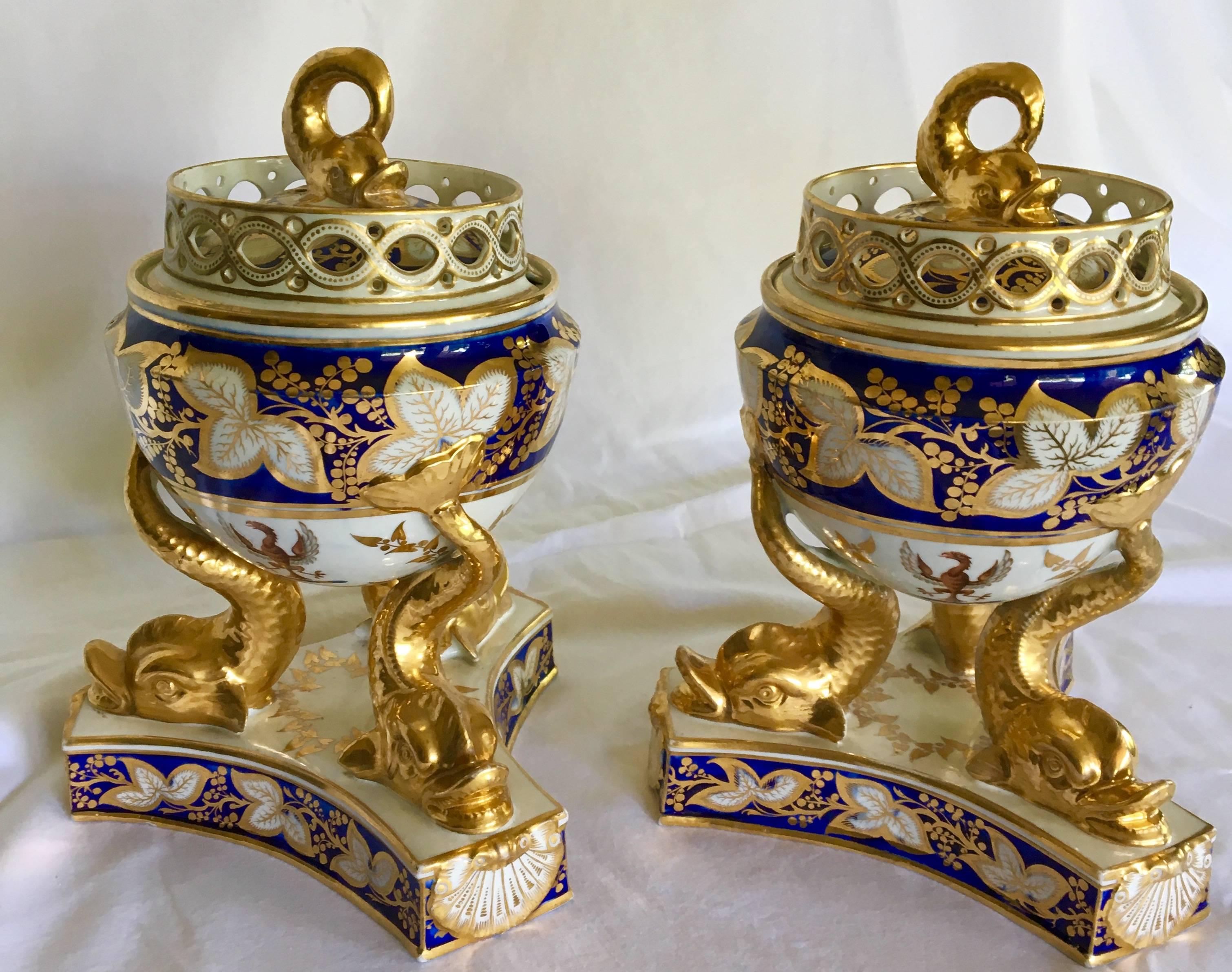 Coppia di zuppiere d'epoca Regency vivacemente dipinte in blu cobalto sottosmalto con supporti e piano d'appoggio a delfino riccamente dorati. Sul lato di ogni zuppiera c'è lo stemma della famiglia Blesset con l'aquila ad ali spiegate. La famiglia