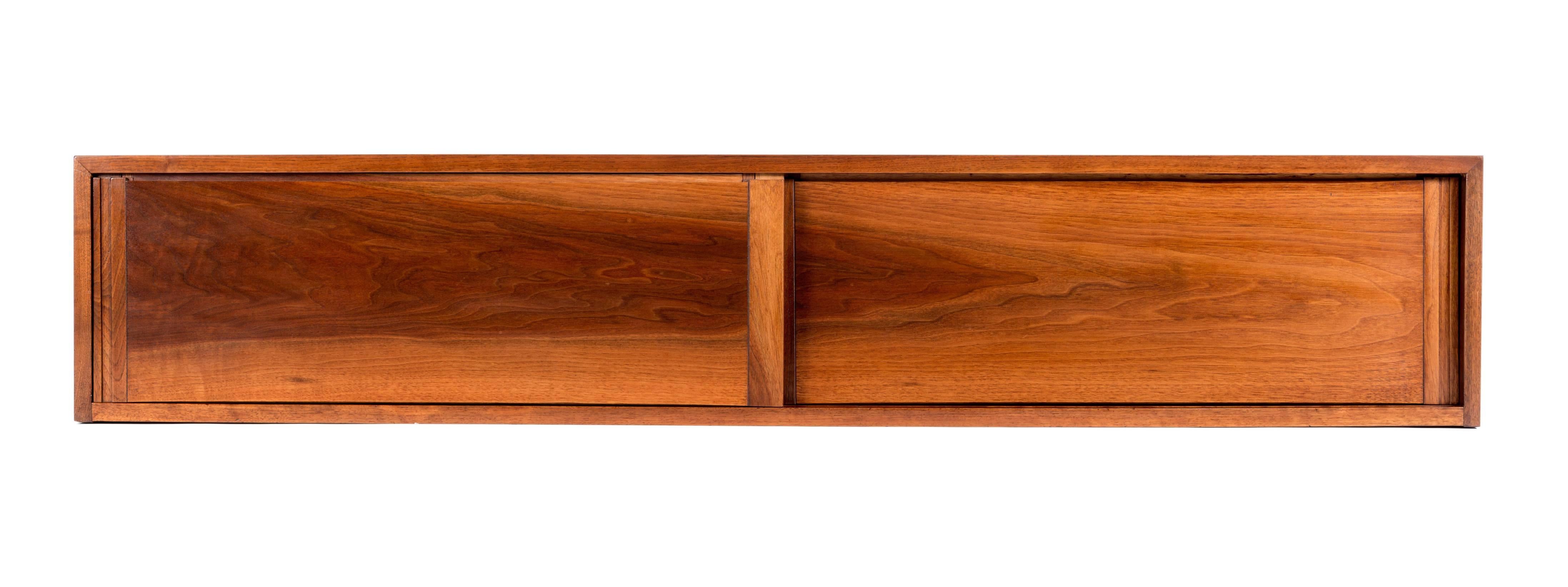Attractive 5 ft. walnut wall-mounted cabinet by George Nakashima. Cabinet features two sliding doors and dove-tailed top. Cabinet with provenance.