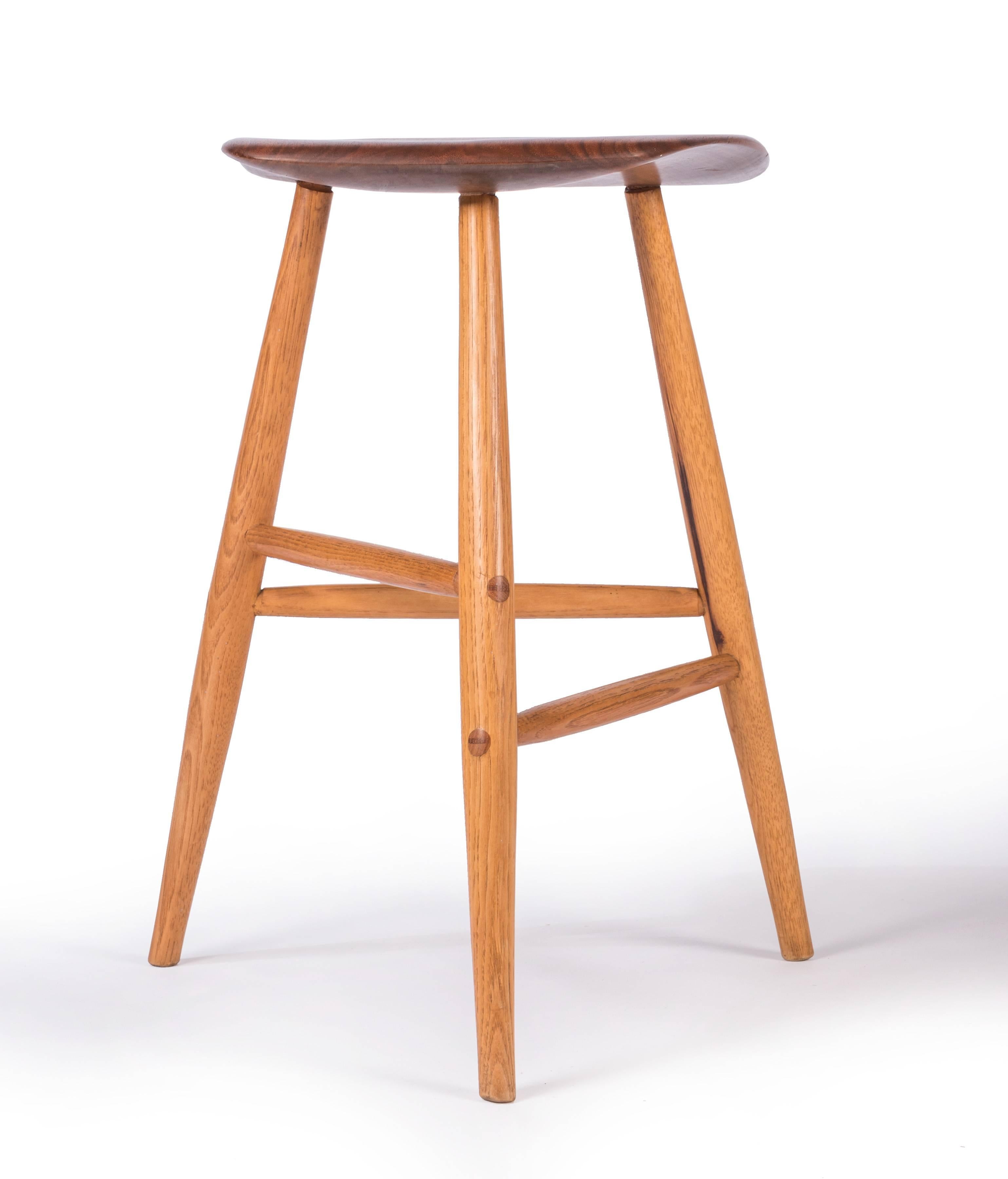Hand-carved stool by Wharton Esherick, the Father of the American Studio Craft Movement. This iconic stool is an excellent example of Esherick's work and features a sculptural free-form walnut seat over three tapered legs of carved oak connected