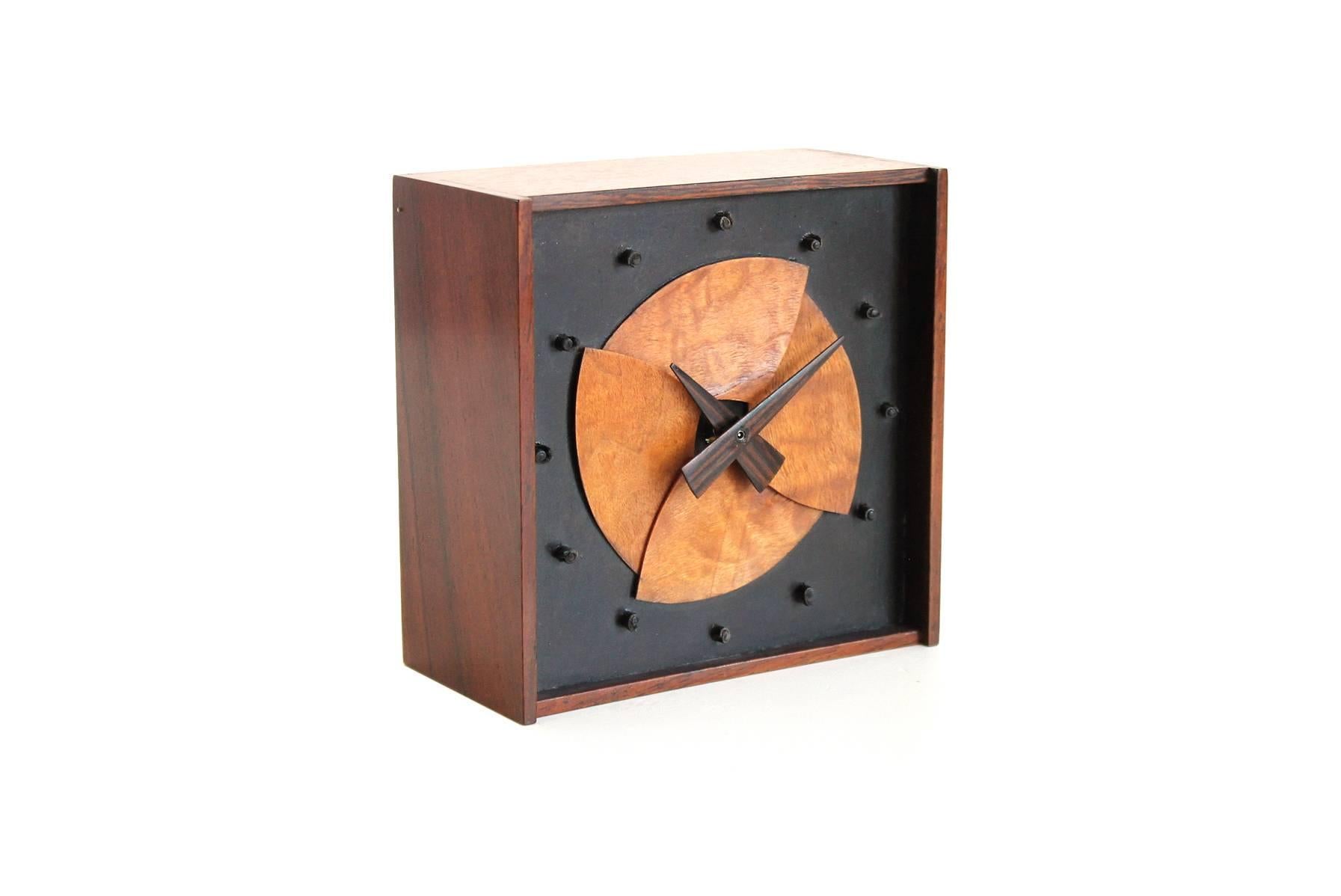 Table clock with mixed exotic woods by master woodworker and craftsman Jere Osgood. Pound bent-stave laminated wood face made of maple, with rosewood case and hands and leather hour markers. Only 8 of these were produced. Battery powered.