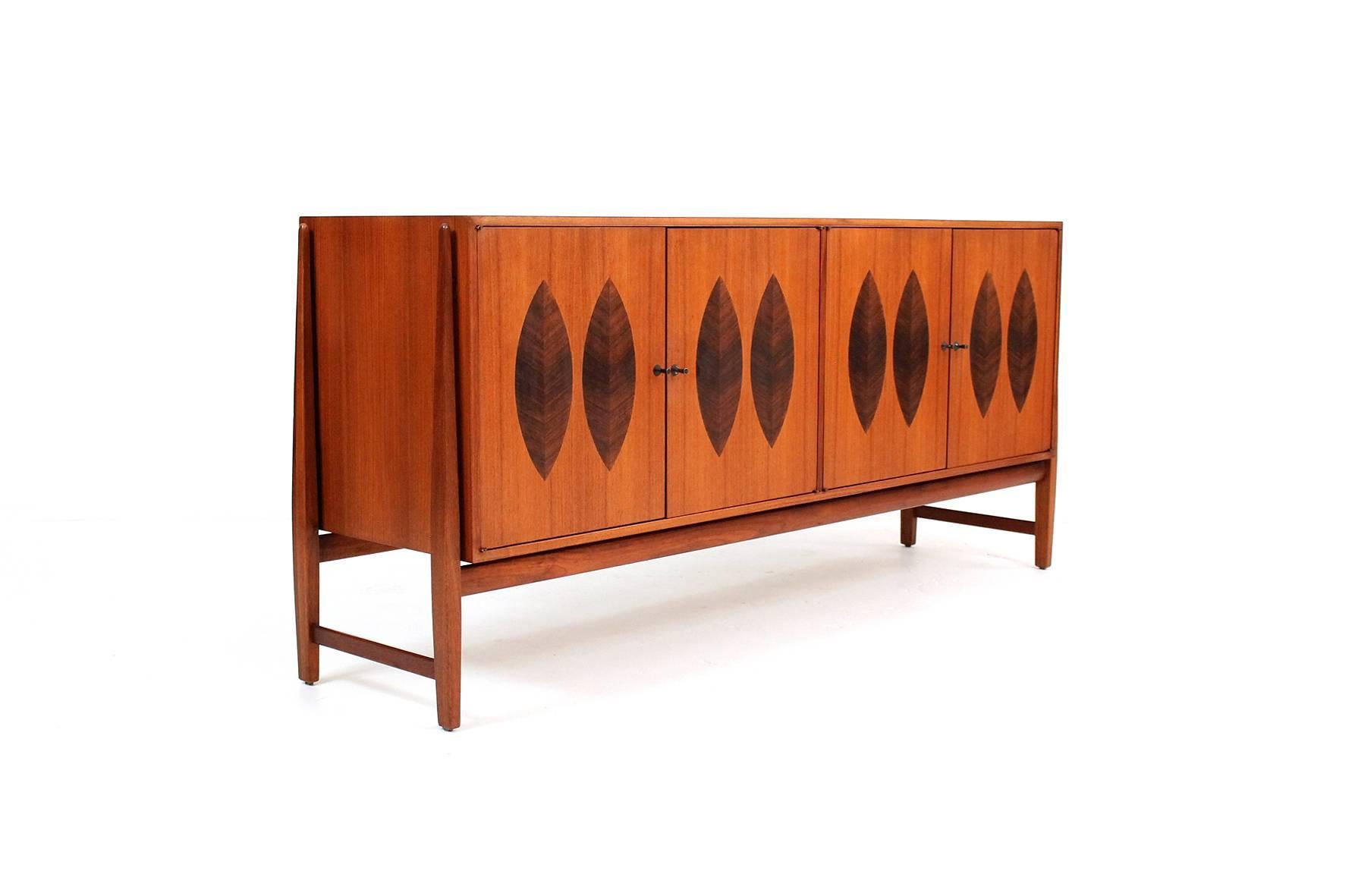 Credenza or cabinet designed by Kipp Stewart for Calvin. Cabinet features four doors with leaf inspired rosewood inlays. Doors open up to reveal a glass shelf of the left and two flatware drawers on the right. Well constructed and styled cabinet.