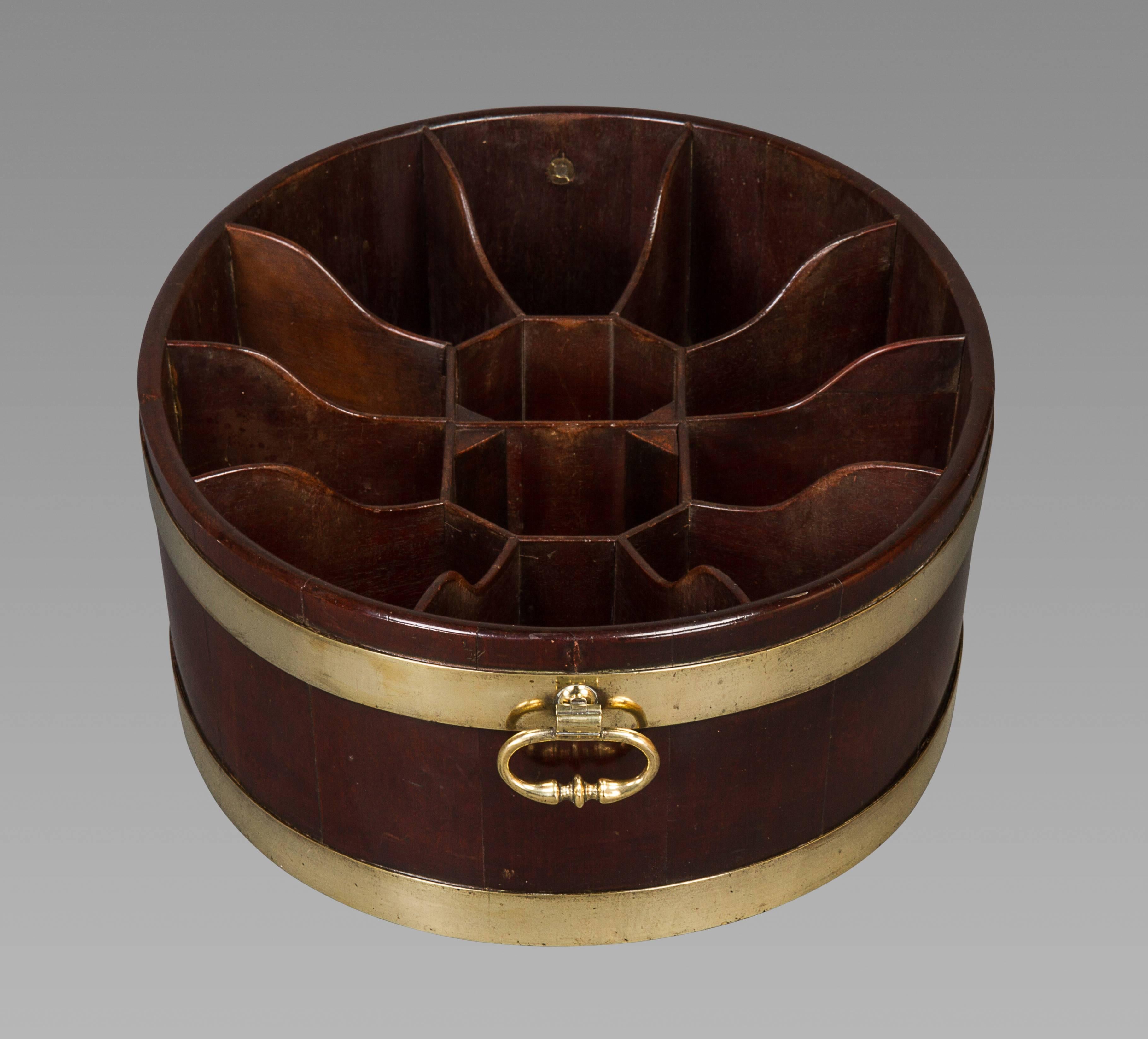Of traditional shape for a wine cooler of the mid to late 18th century, this piece is somewhat of a conundrum. The brass bound staved oval piece has a fitted interior divided into twelve sections that are original to the piece. On first glance it
