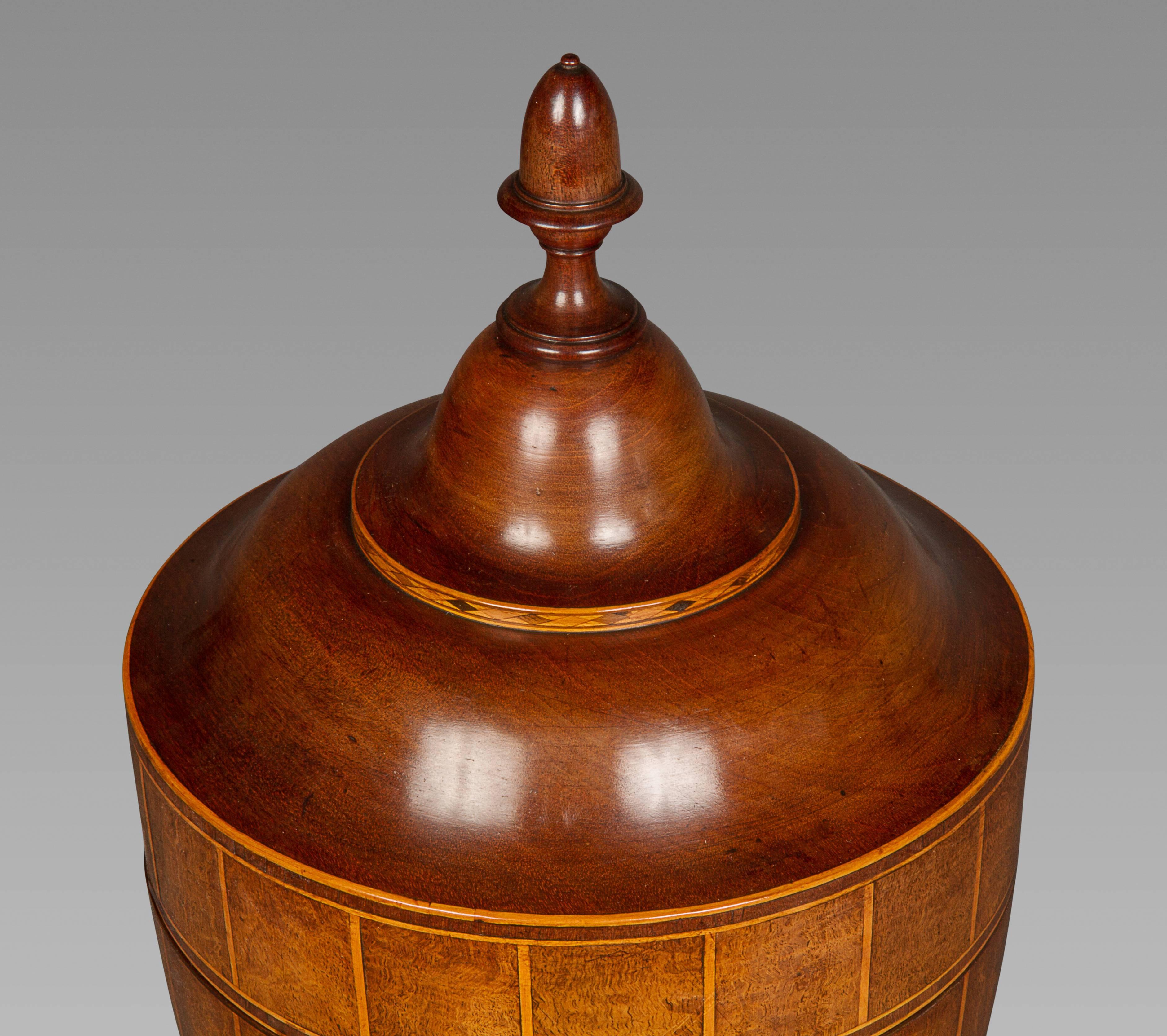 A superb pair of period urns with acorn finials, the bodies veneered in alternating panels of mahogany and beautifully figured burr mahogany, inlaid with satinwood stringing, on stepped square bases, with original felt to the bases. The color and