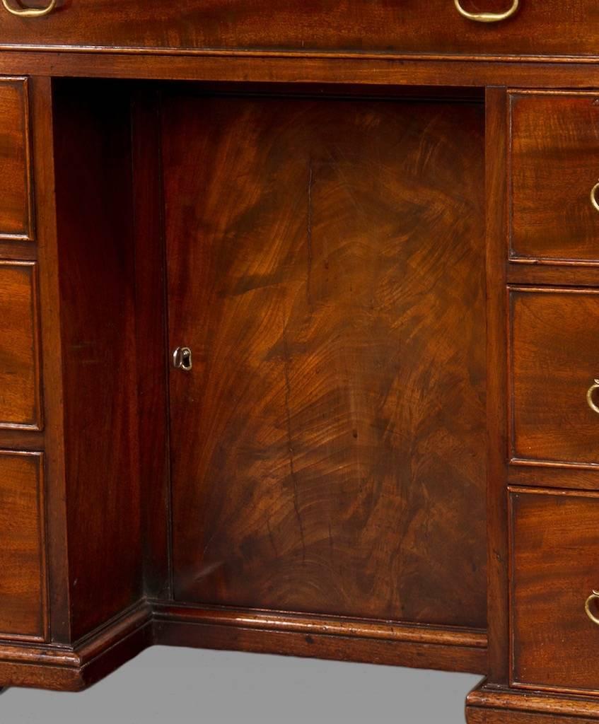 With one long drawer to the frieze over two columns of three short draws with a recessed cupboard between ending in the original bracket feet. This small desk is of excellent quality and craftsmanship constructed of well figured dense Cuban