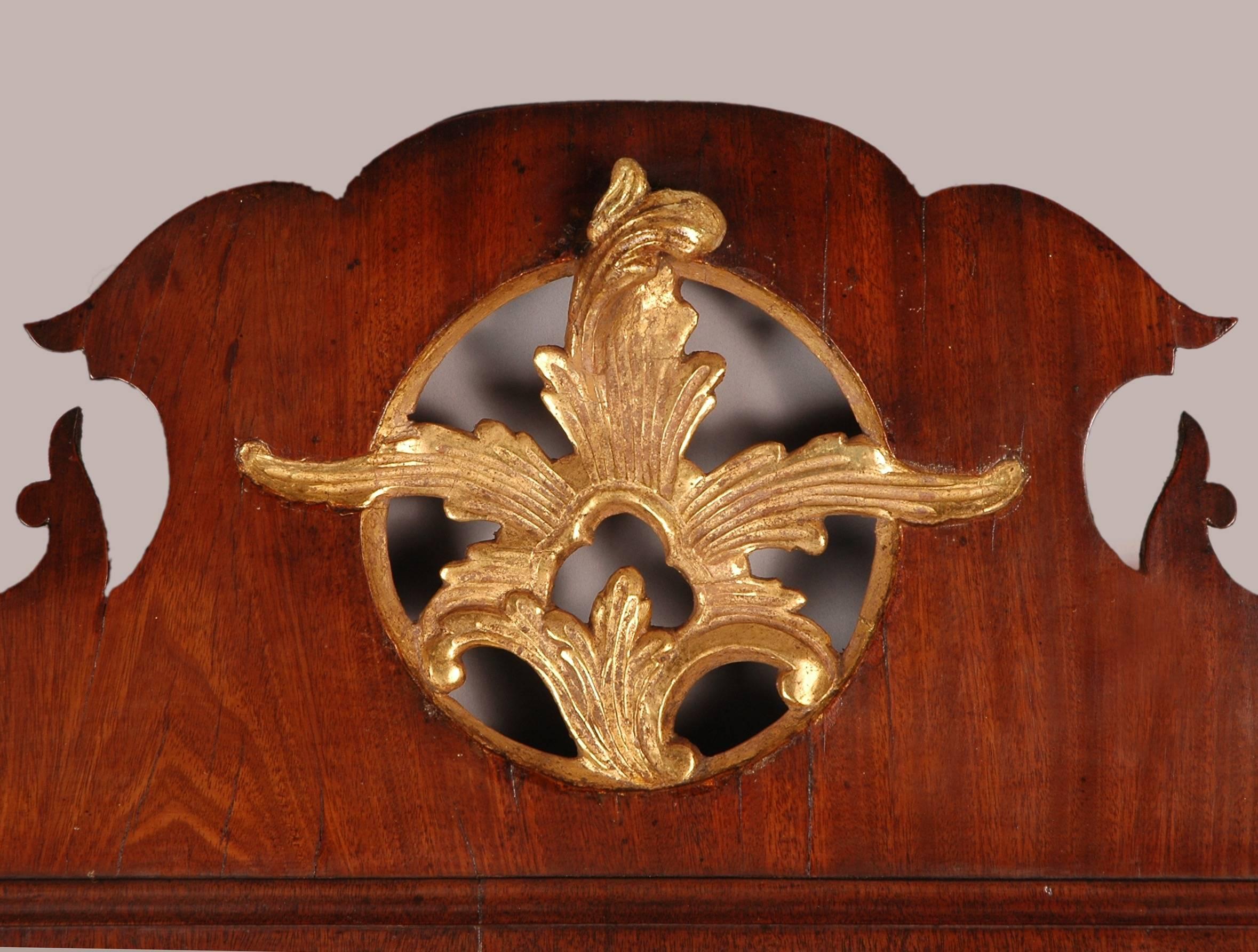 With a pierced cresting containing a shaped gilt leaf decoration to the roundel, the sides flanked by gilt pendant foliate garlands and a shaped apron. Mirror plate possibly replaced.