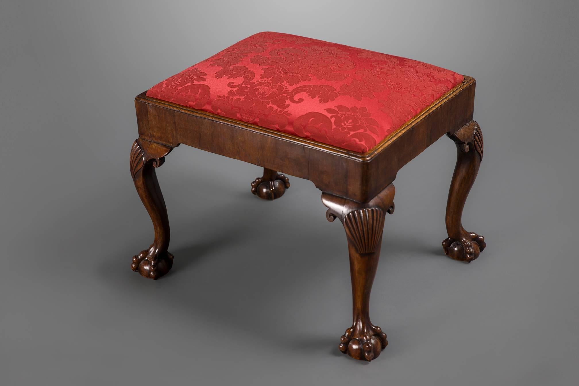 A rather good rectangular stool is walnut with shell curved knees and ball and claw feet, cornered in a deep red scalamandre silk and retaining the original drop in seat.

Provenance: Estate of Carroll Petrie New York.

English, circa 1740.