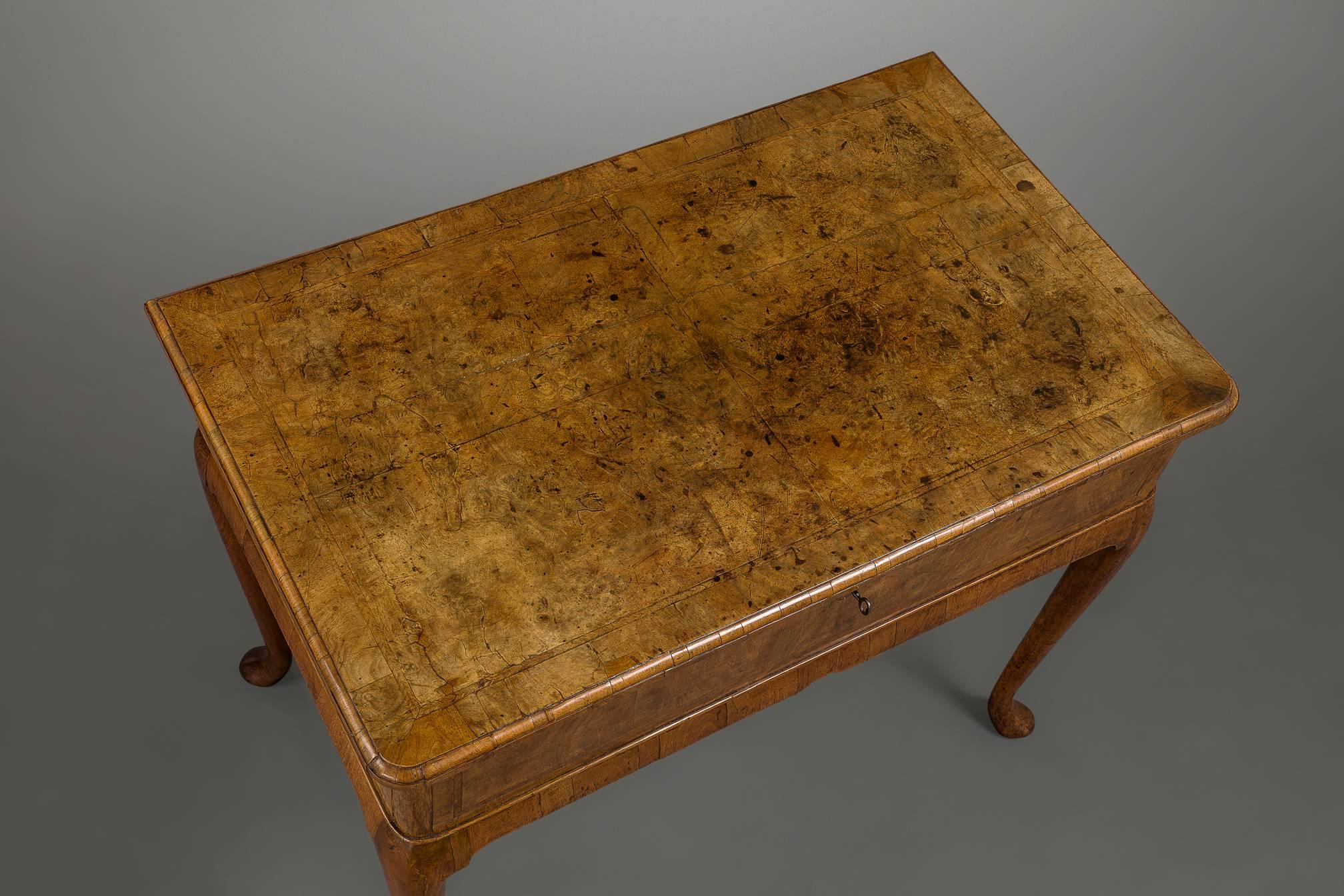 Standing on elegant tapering legs with a slight cabriole and pad feet this table has the most unusual feature of a lockable lift-up top for the storage of valuables. The top is veneered in quartered burr veneer of glorious color with herring-bone