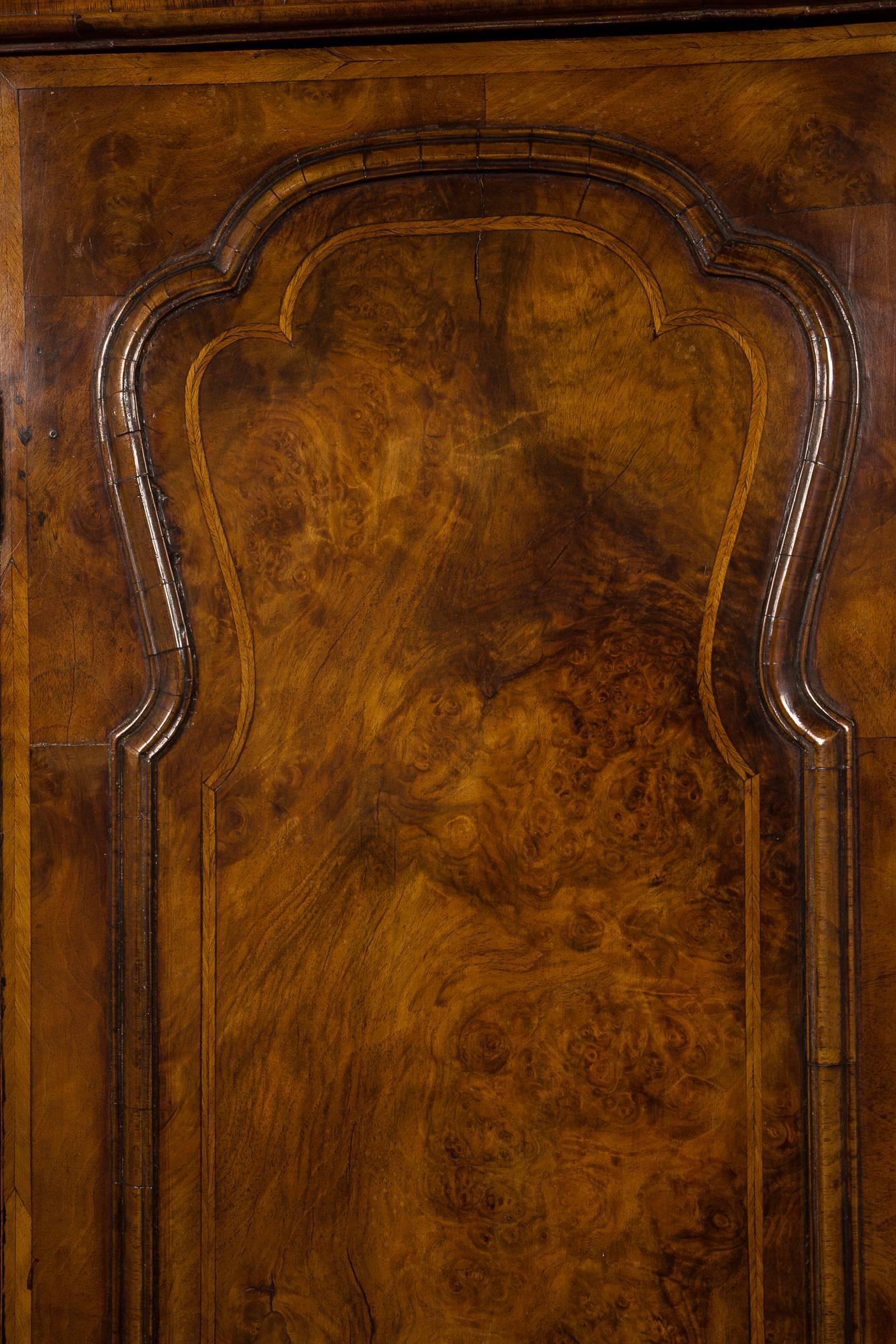 A good quality cupboard in two sections with fine matched and highly figured walnut veneers. Each section opening to heart shaped shelves and the whole standing on tall bracket feet. The hinges, originally the shaped, replaced probably in the 19th