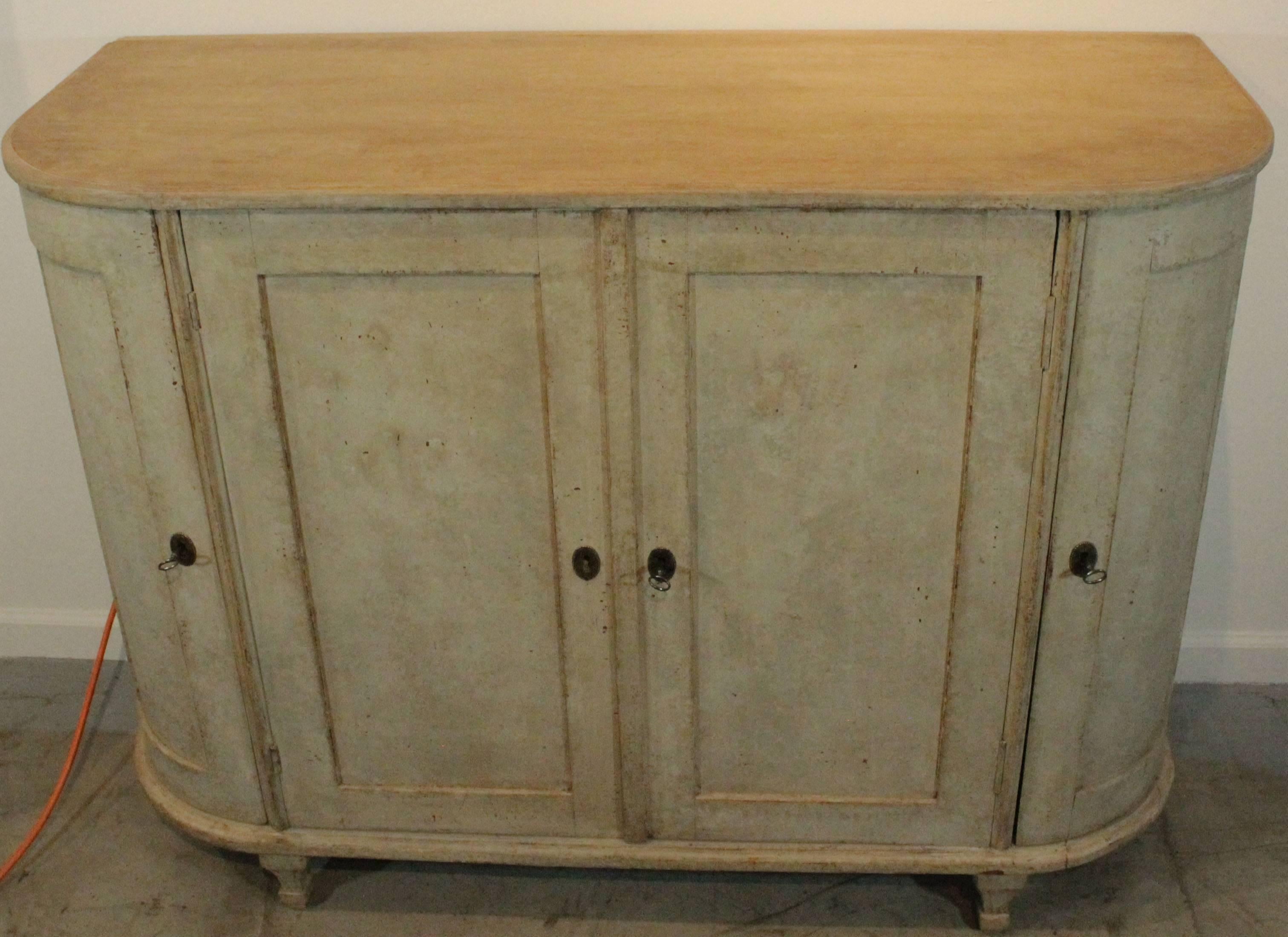 Antique Swedish sideboard with curved sides, early 19th century.
Four-door sideboard with large center storage shelves and two hidden drawers. Behind the curved doors are three additional shelves on each side. The piece is painted a light greenish