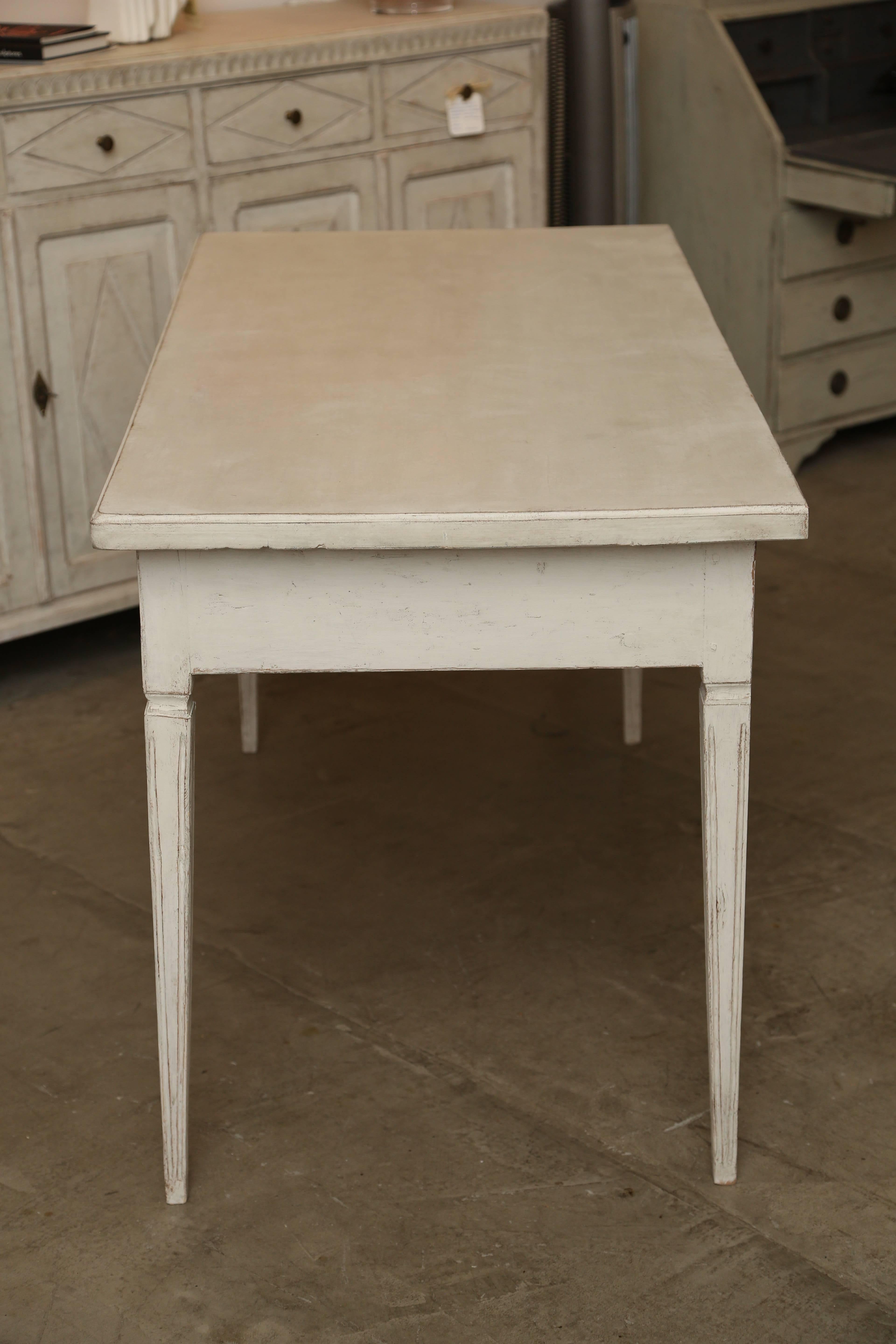 Large antique Swedish period writing desk with refreshed Gustavian distressed white paint and two carved ribbed drawers. Sits beautifully on tapered fluted legs.

Measures: 31.25'' high
58.25'' wide
27.75'' deep.