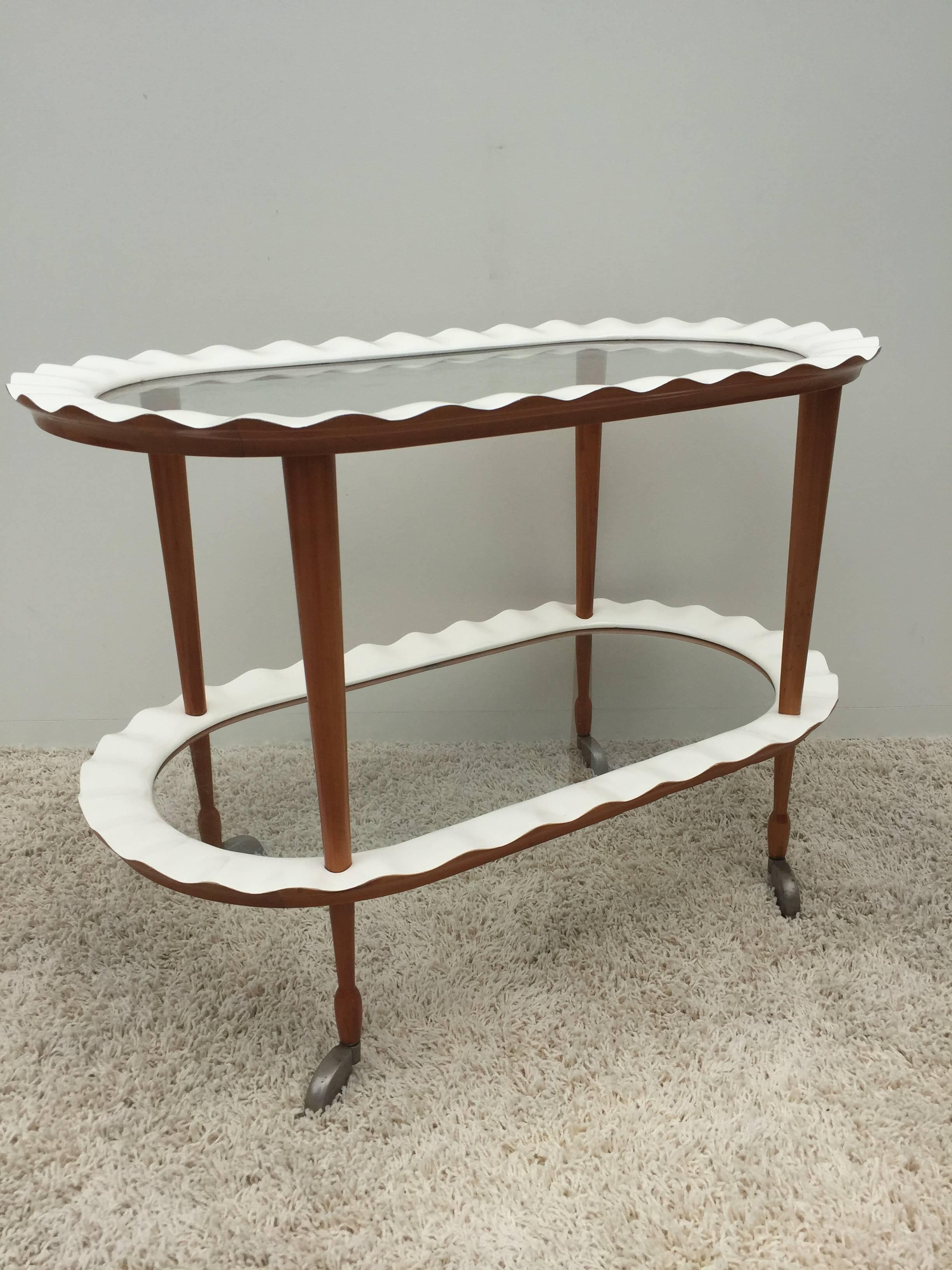 Italian creme lacquered and mohagany, glass two-tiered waved edge rolling cart.