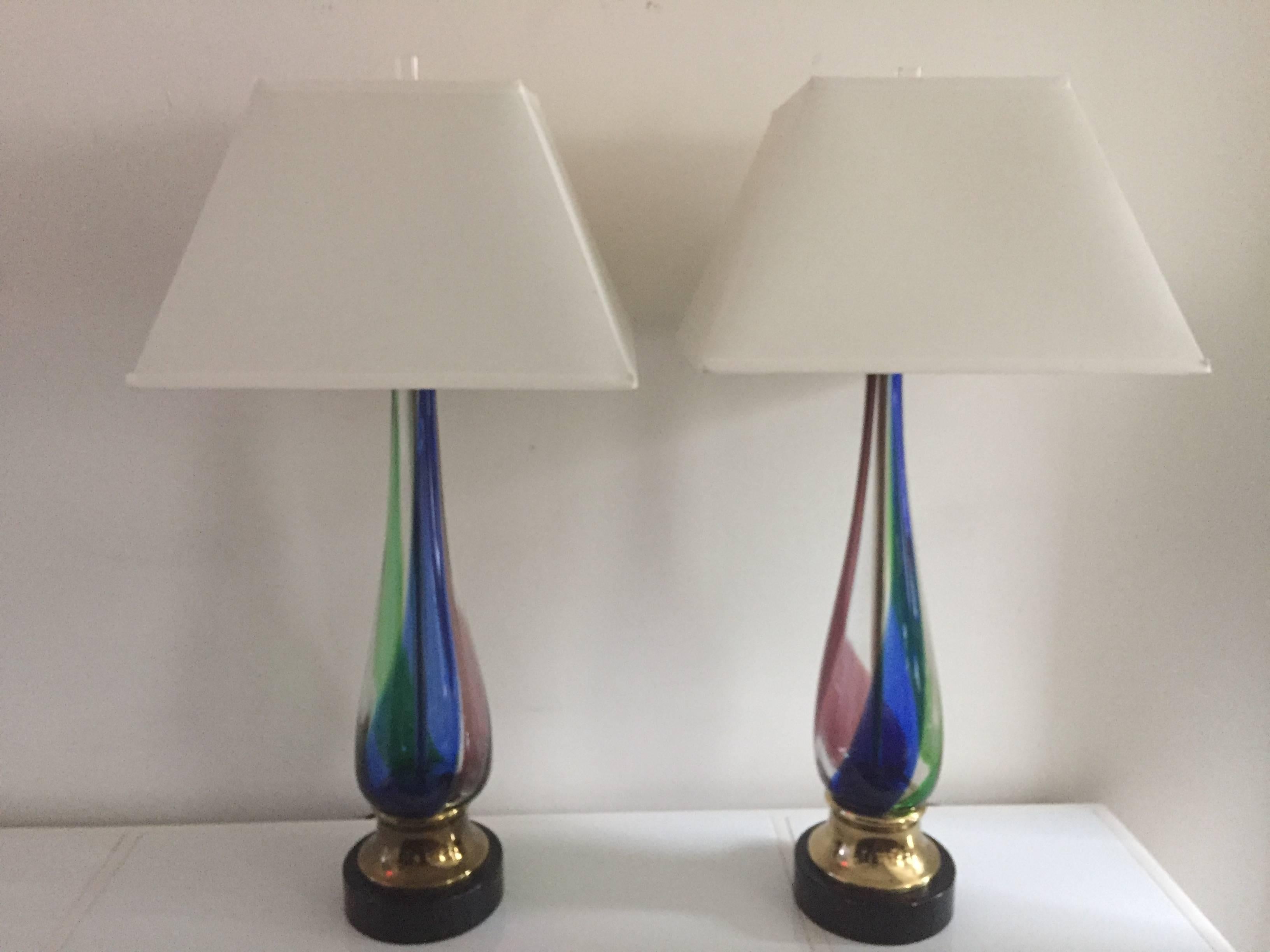 Pair of Murano Venetian lamps In colored glass swirl design, purple green blue and clear, with black lacquered and brass base vintage and extra large tall lamps.

The height as shown 36