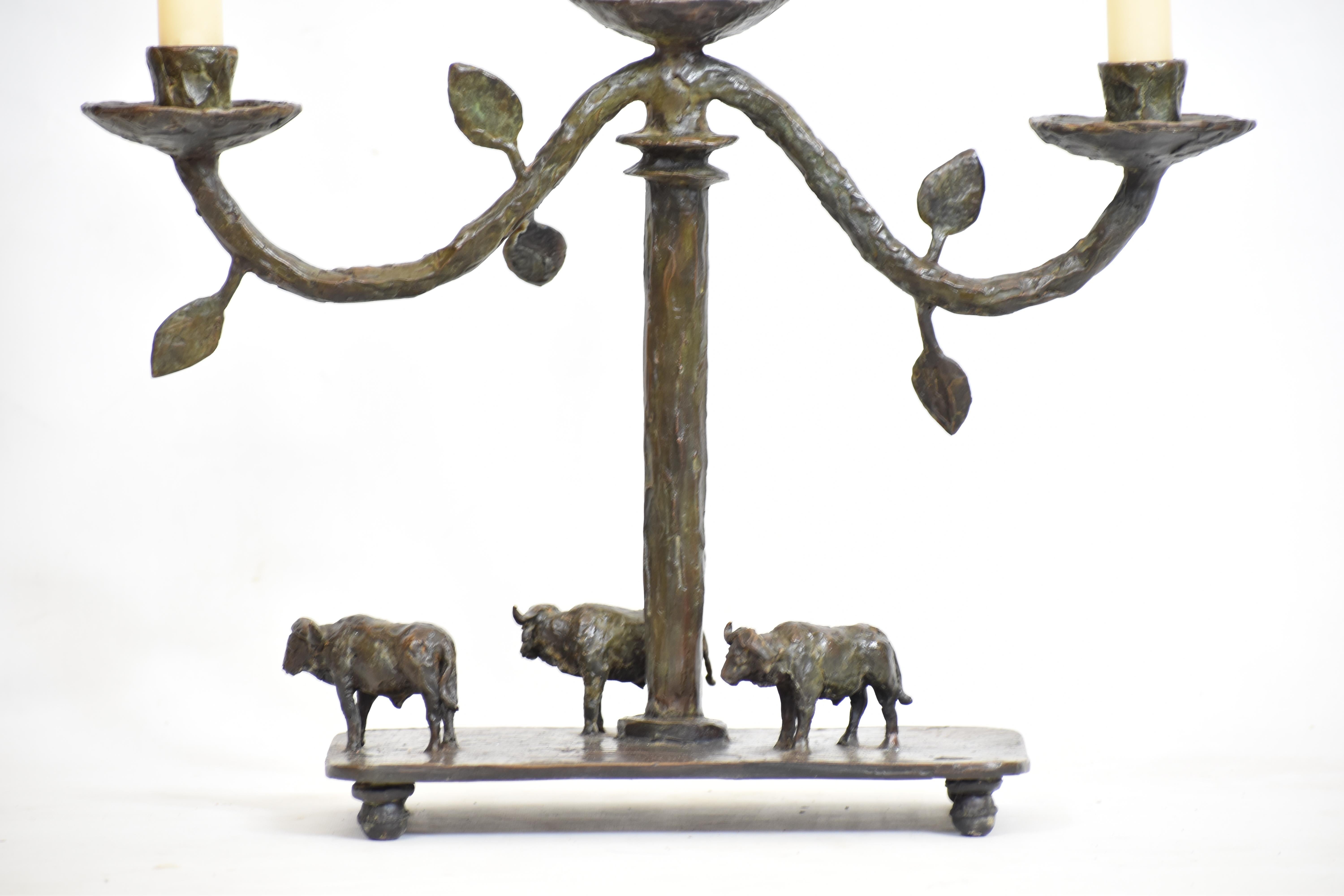 This handcrafted bronze candelabra is a sculptural tribute to the quiet strength and unity of the African buffalo. Three candleholders rise from gently curving branches adorned with leaves, while below, a trio of buffalo stand grounded on a textured