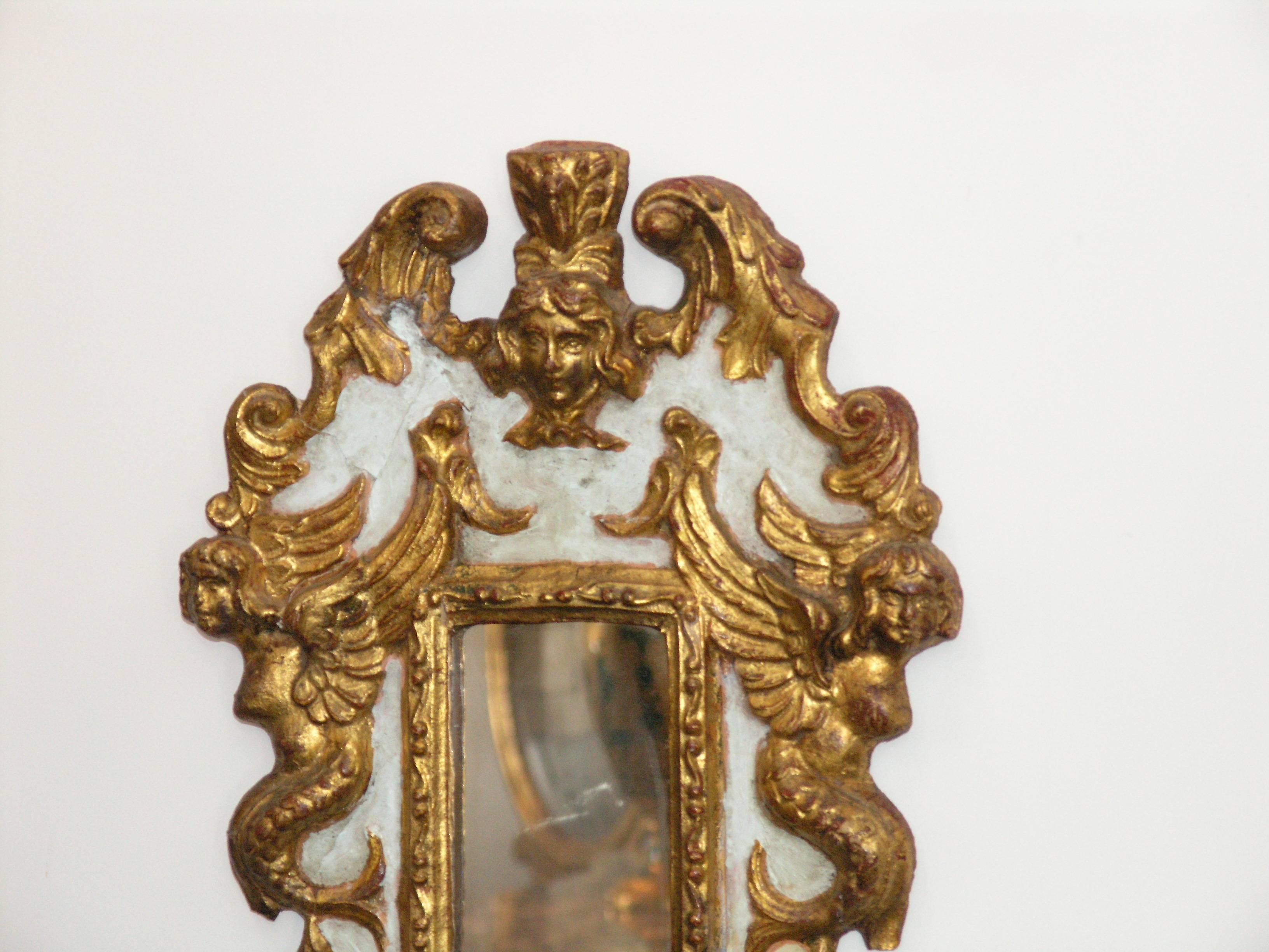The rectangular mirror plate within a scrolling foliate border surmounted by a cherub head cresting and similar shaped apron below.