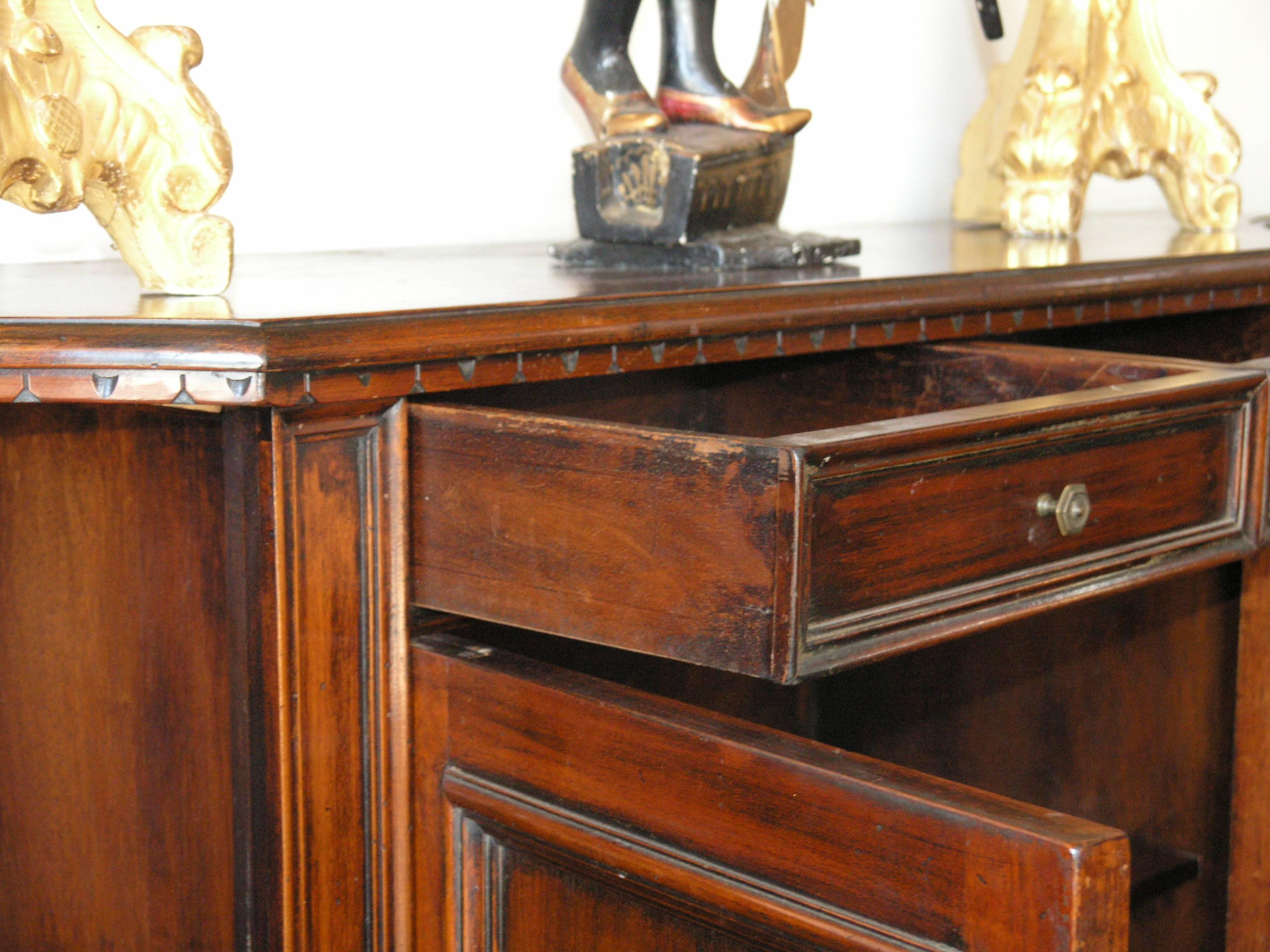 The serpentine breakfront outline top with molded edge, fitted with two frieze drawers above four paneled cupboard doors on a molded base with scrolled bracket feet.