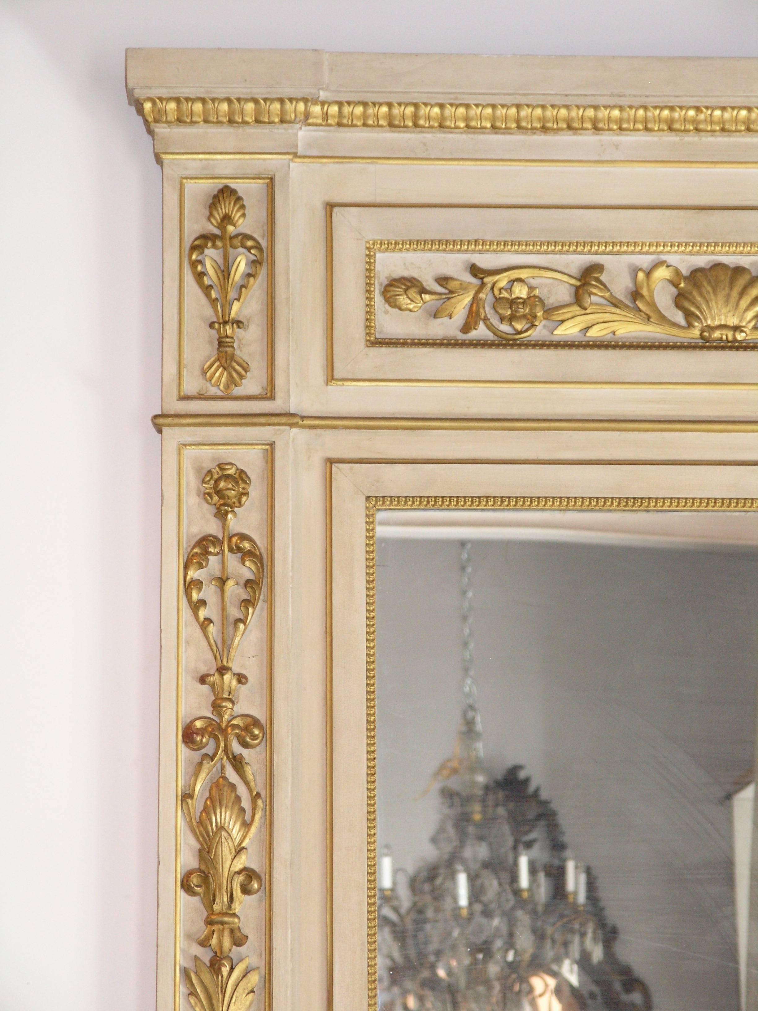 Pair of giltwood and ivory painted Northern Italian pier mirrors. The rectangular cornice with leaf tipped frieze above a ribbon tied floral swag, the rectangular plate within paneled stiles decorated and ending on a plinth base.