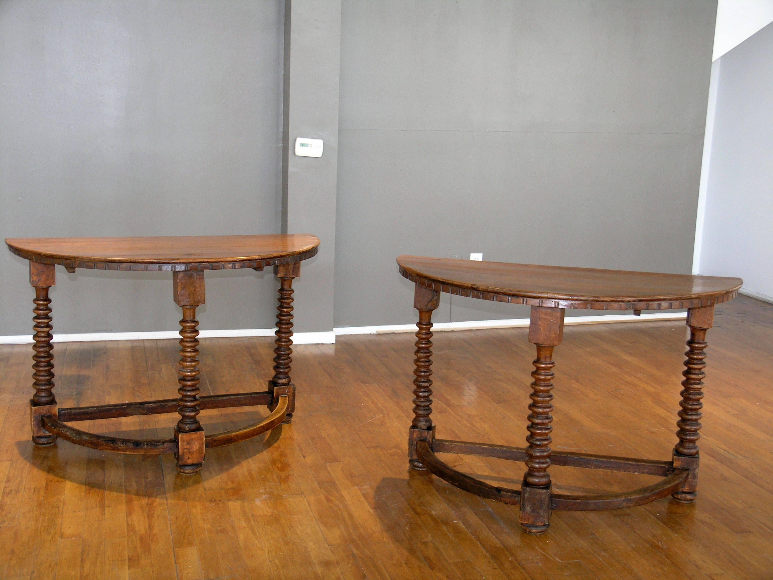 Demilune walnut tops with molded edge above a shallow chip carved frieze raised on barley twist legs joined by stretchers on later compressed ball feet.