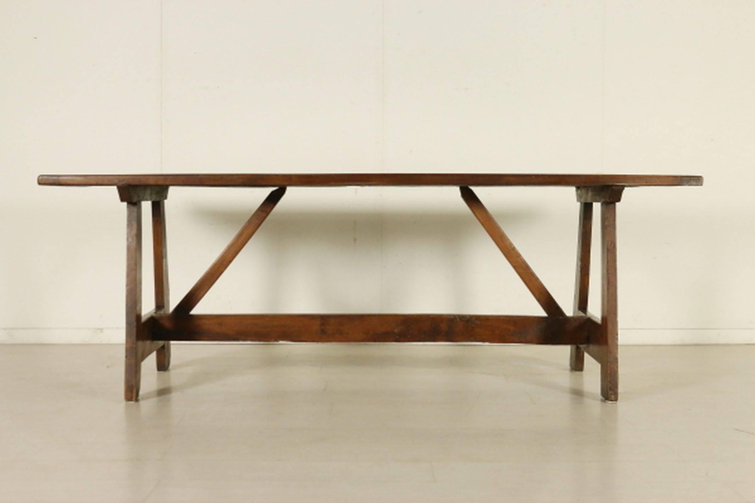 Rectangular walnut top raised on trestles joined by stretchers.