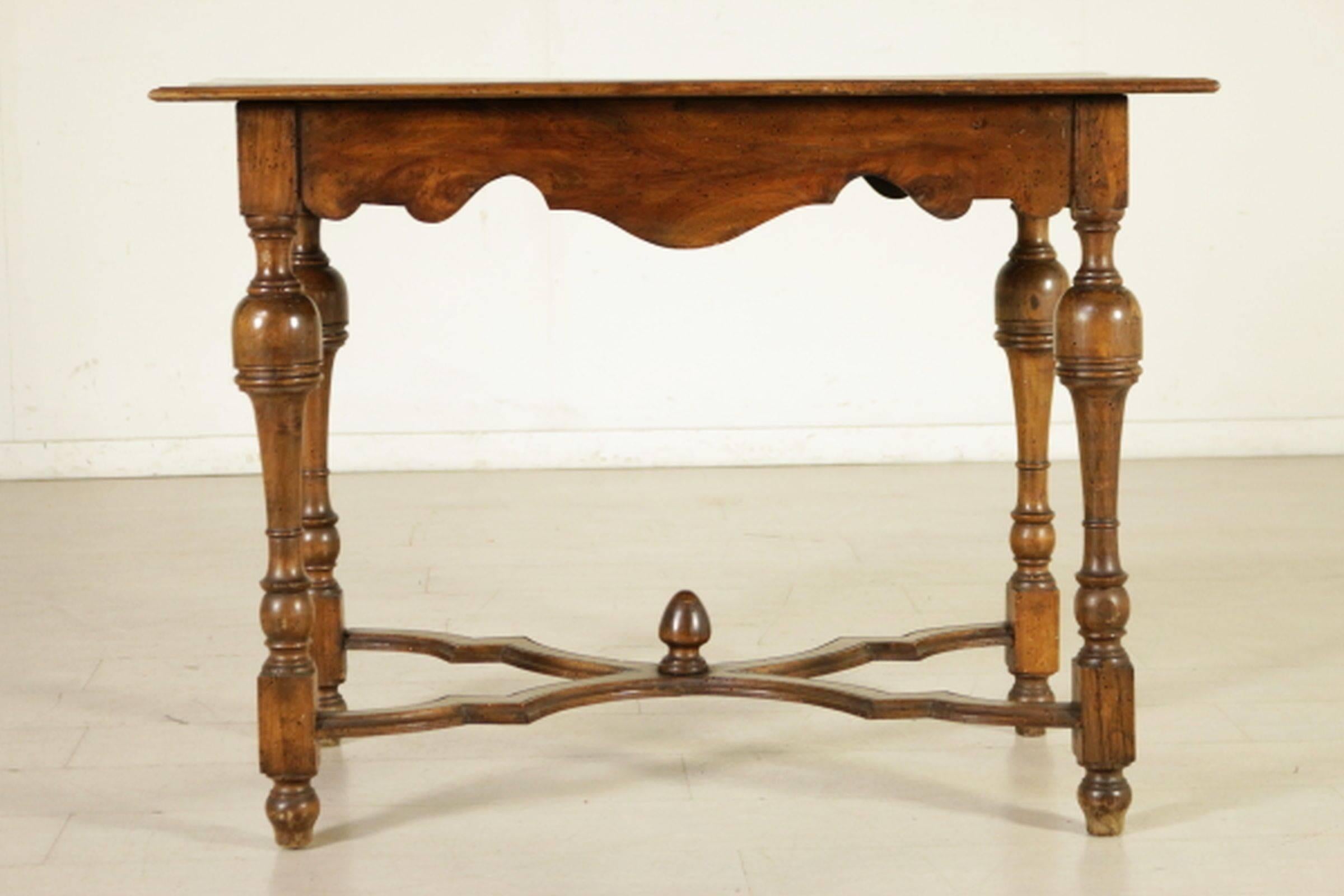 Rectangular top with molded edge above a shaped frieze with a single drawer raised on baluster turned legs ending on compressed bun feet joined by an incurving stretcher.