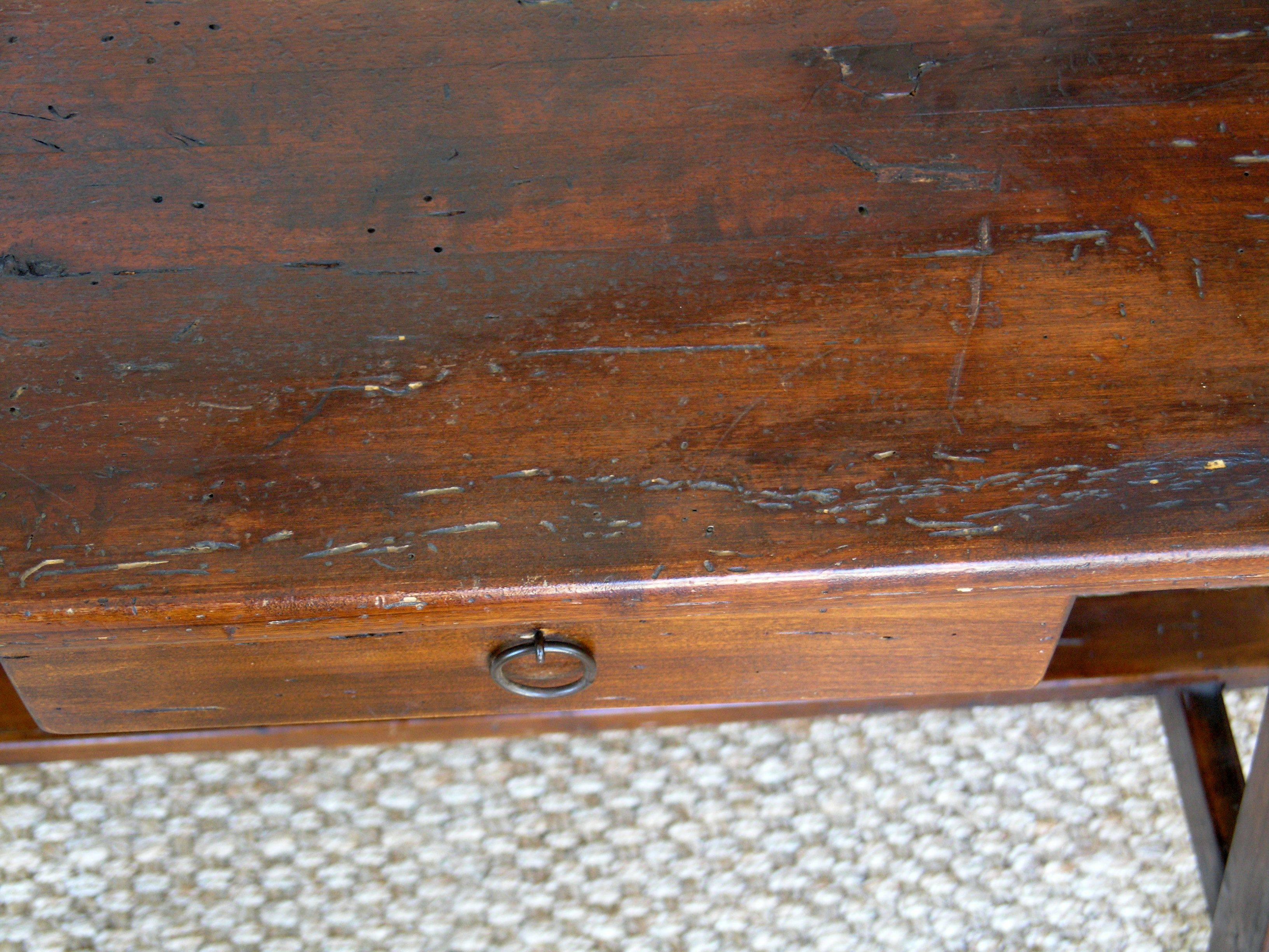 Rectangular top above a long drawer raised on trestles joined by stretchers.