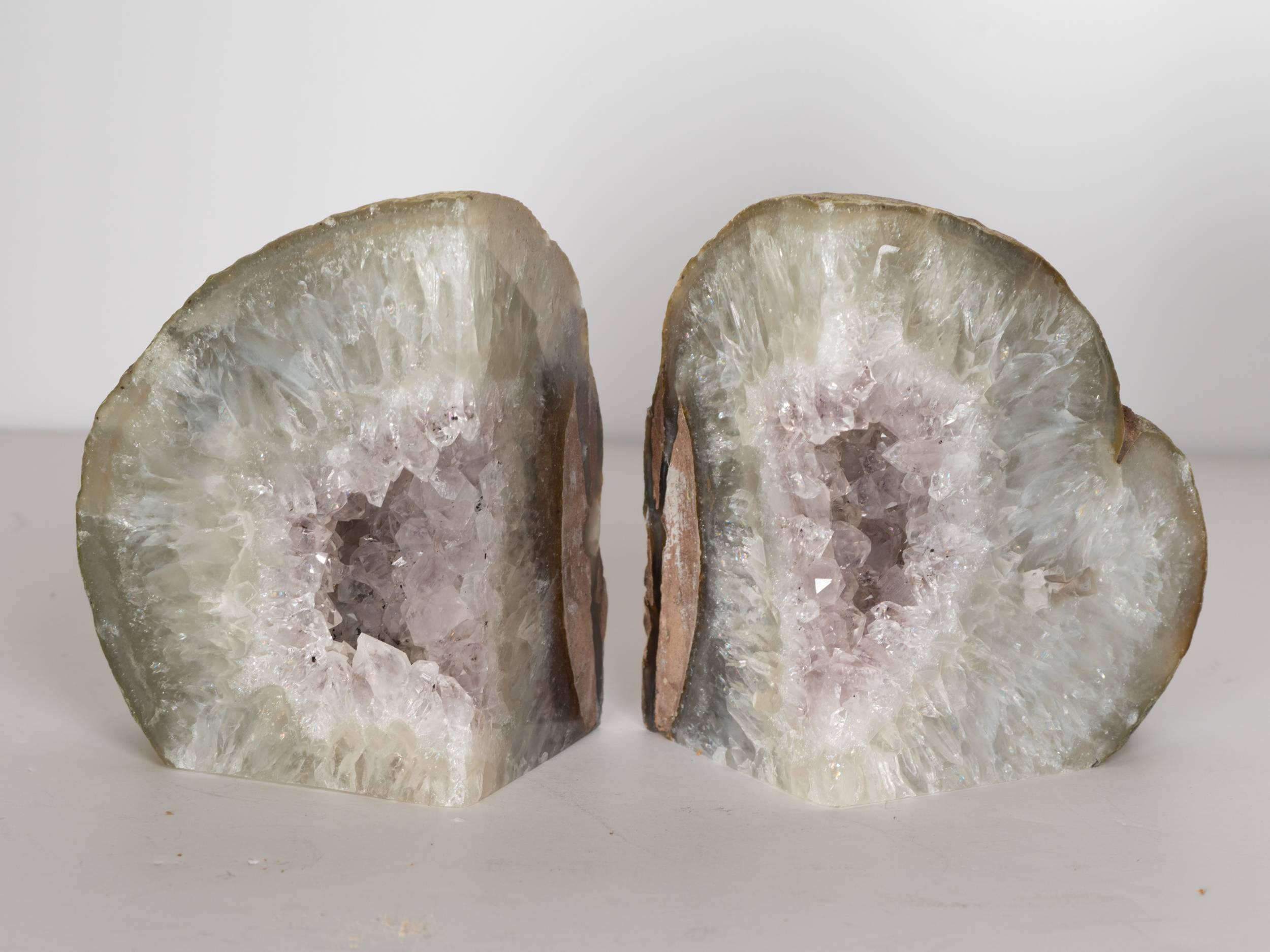 Outstanding pair of natural quartz crystal bookends with solid polished fronts and rough exterior edges. Sculptural shape in variant shades of grey and white, with exquisite amethyst crystal centers in hues of pale violet. Beautiful from all angles