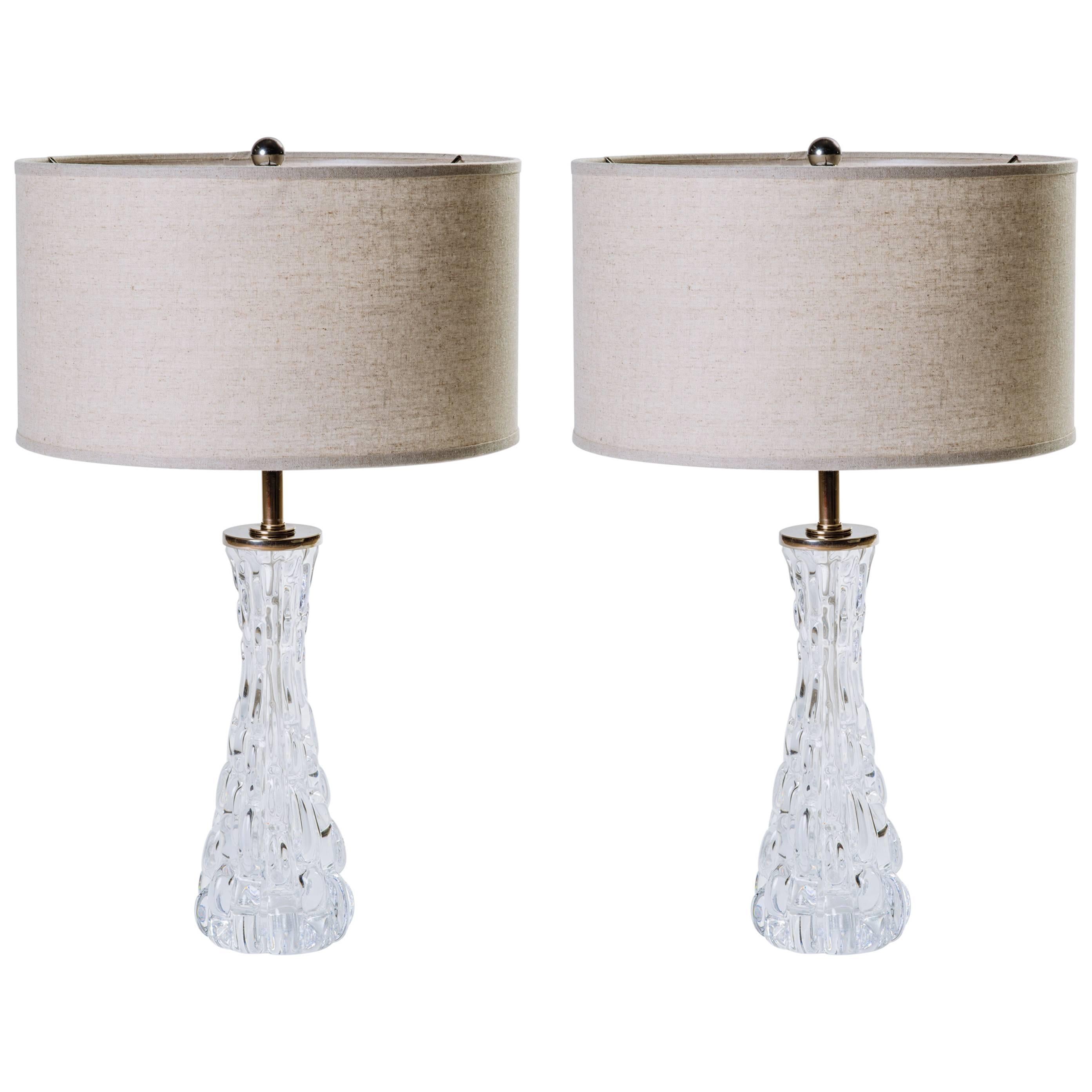 Pair of stunning Mid-Century Modern Swedish crystal lamps. The lamps have hourglass forms with textured ice glass design. Nickeled stem and fittings and shown with custom pale grey linen drum shades.